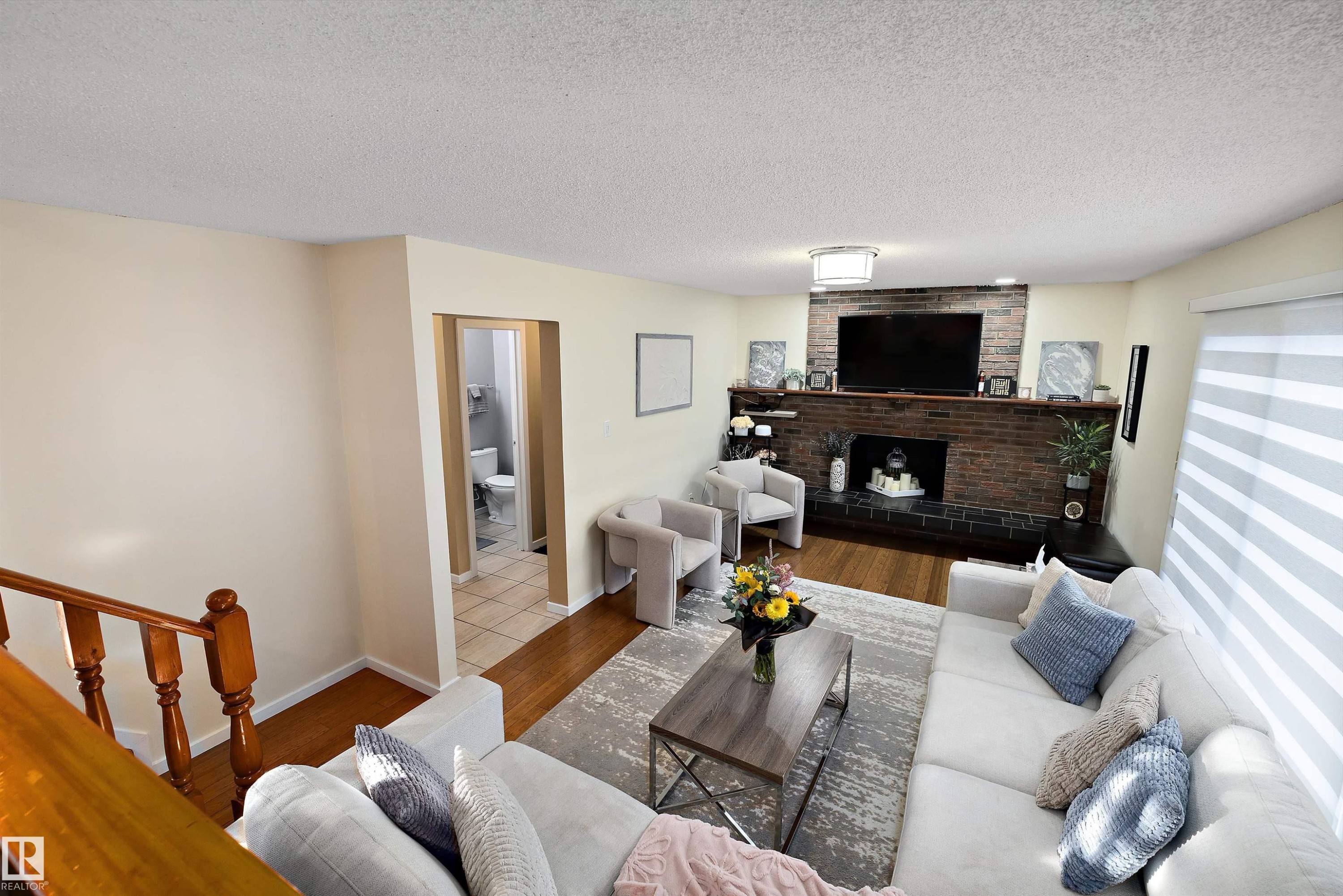 Living area featuring wood finished floors, a fireplace, and a textured ceiling - 9804 156 Avenue, Edmonton, AB - Indoor Photo Showing Living Room With Fireplace