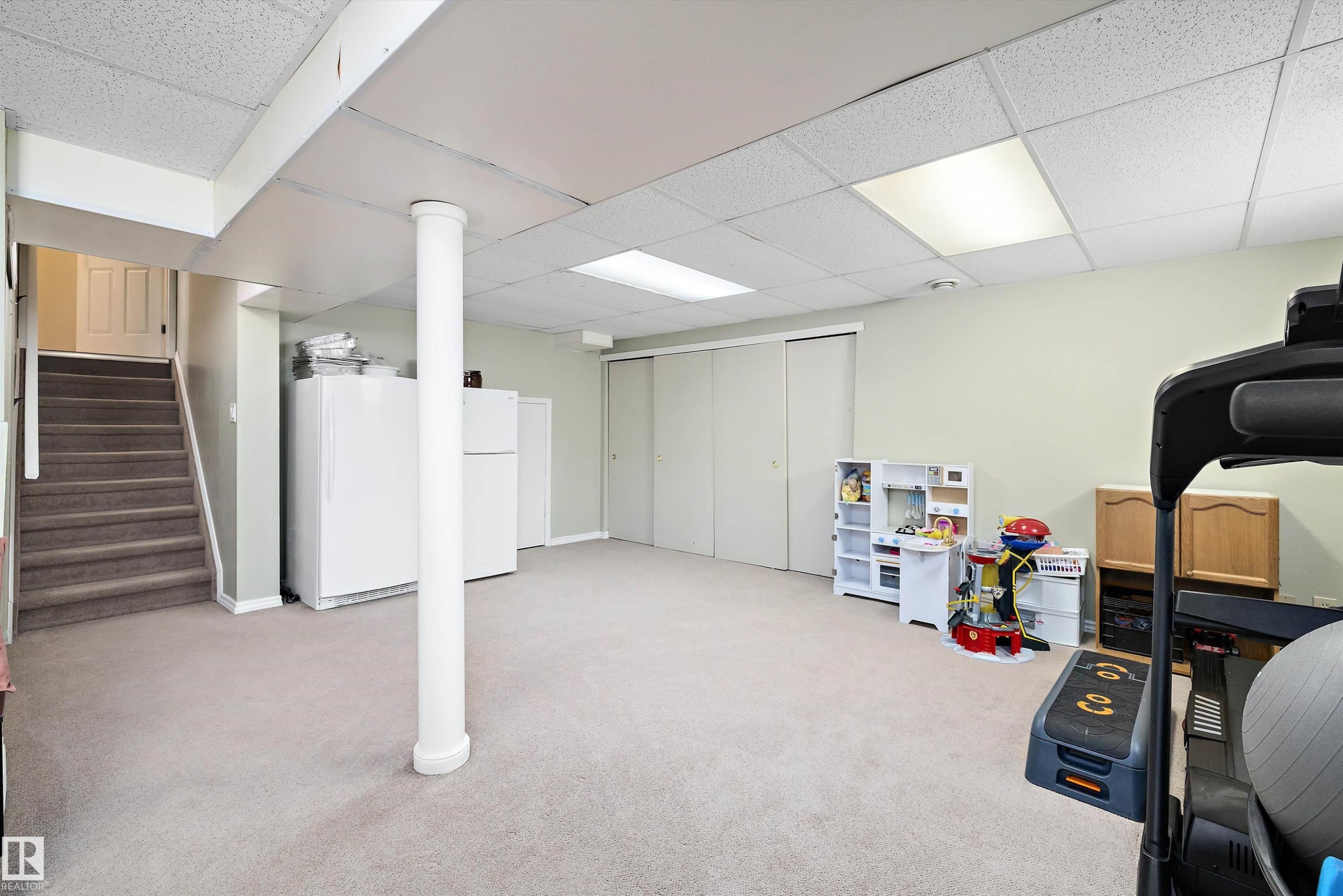 Finished basement with a drop ceiling, carpet flooring, and freestanding refrigerator - 9804 156 Avenue, Edmonton, AB - Indoor Photo Showing Basement
