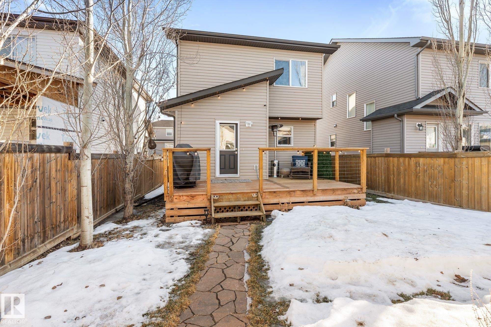 Snow-covered property with a fenced backyard, wooden deck, and pathway - 89 Hewitt Circle, Spruce Grove, AB - Outdoor With Deck Patio Veranda