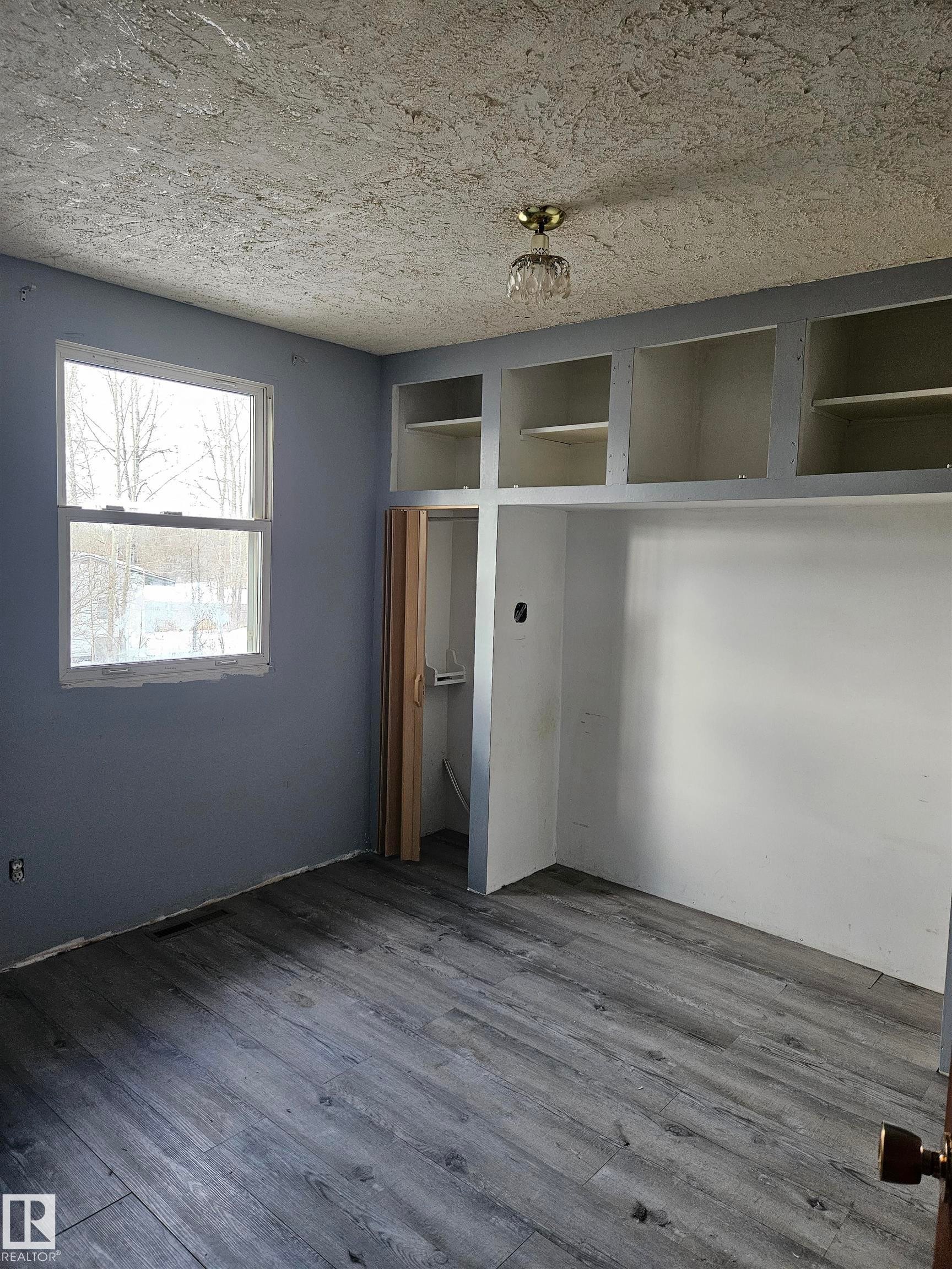 Unfurnished bedroom with dark wood finished floors, a closet, and a textured ceiling - 5314 57 Street, Cold Lake, AB - Indoor