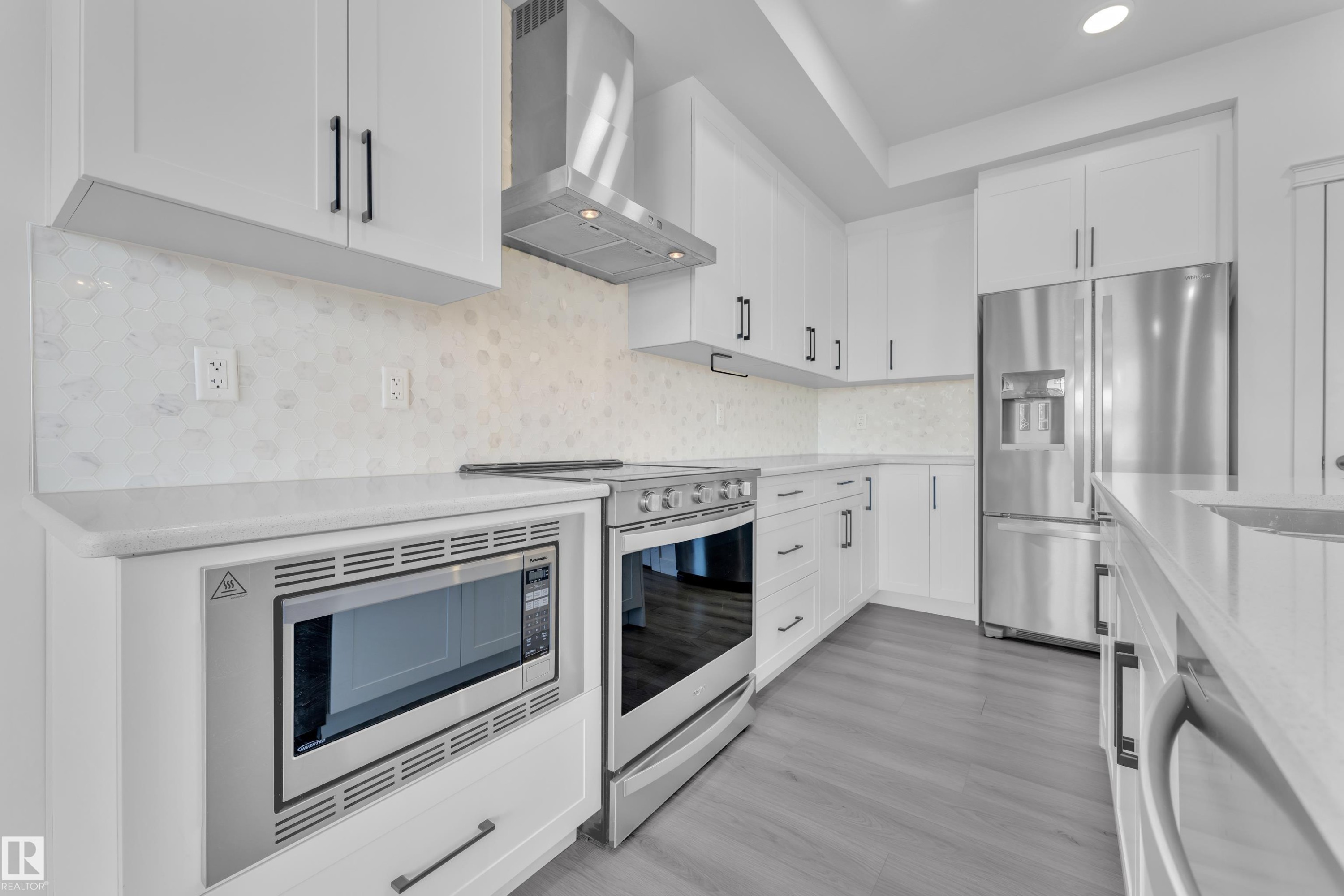 Kitchen with stainless steel appliances, white cabinets, tasteful backsplash, light stone countertops, and recessed lighting - 1822 Collip View, Edmonton, AB