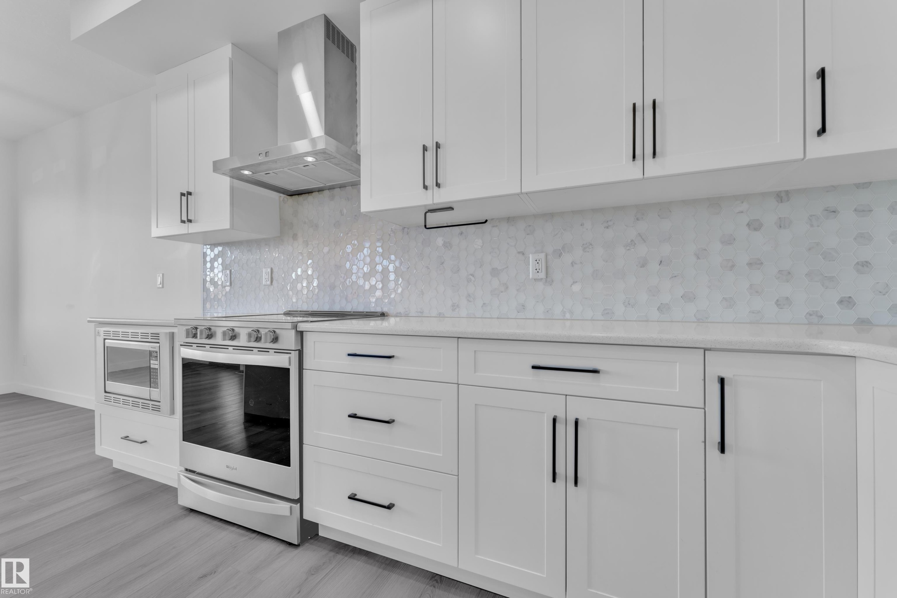 Kitchen featuring stainless steel appliances, white cabinetry, light stone countertops, tasteful backsplash, and light wood-style floors - 1822 Collip View, Edmonton, AB