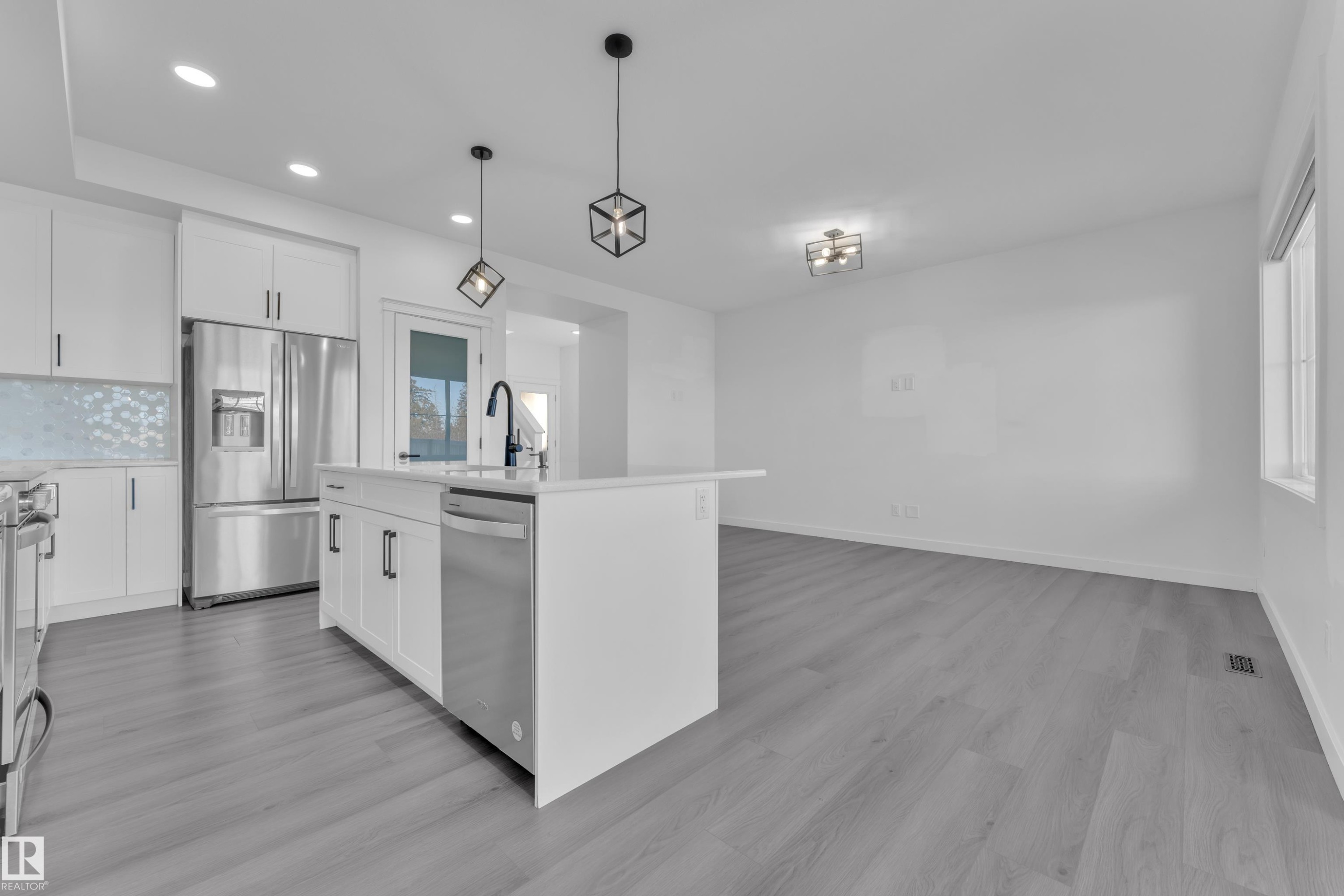 Kitchen featuring white cabinets, stainless steel appliances, pendant lighting, an island with sink, and light wood-style floors - 1822 Collip View, Edmonton, AB