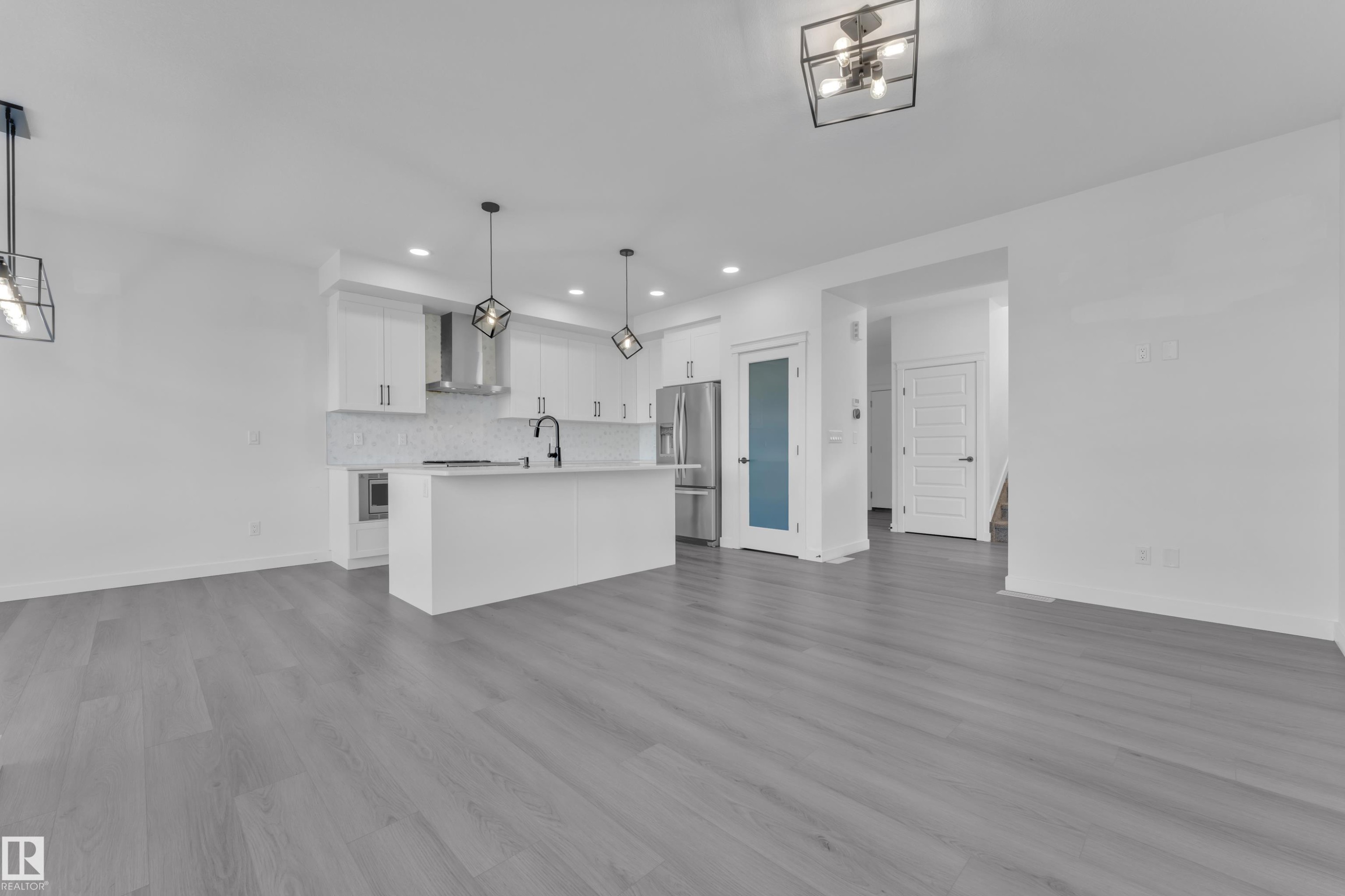 Kitchen with open floor plan, an island with sink, stainless steel fridge, and white cabinetry - 1822 Collip View, Edmonton, AB