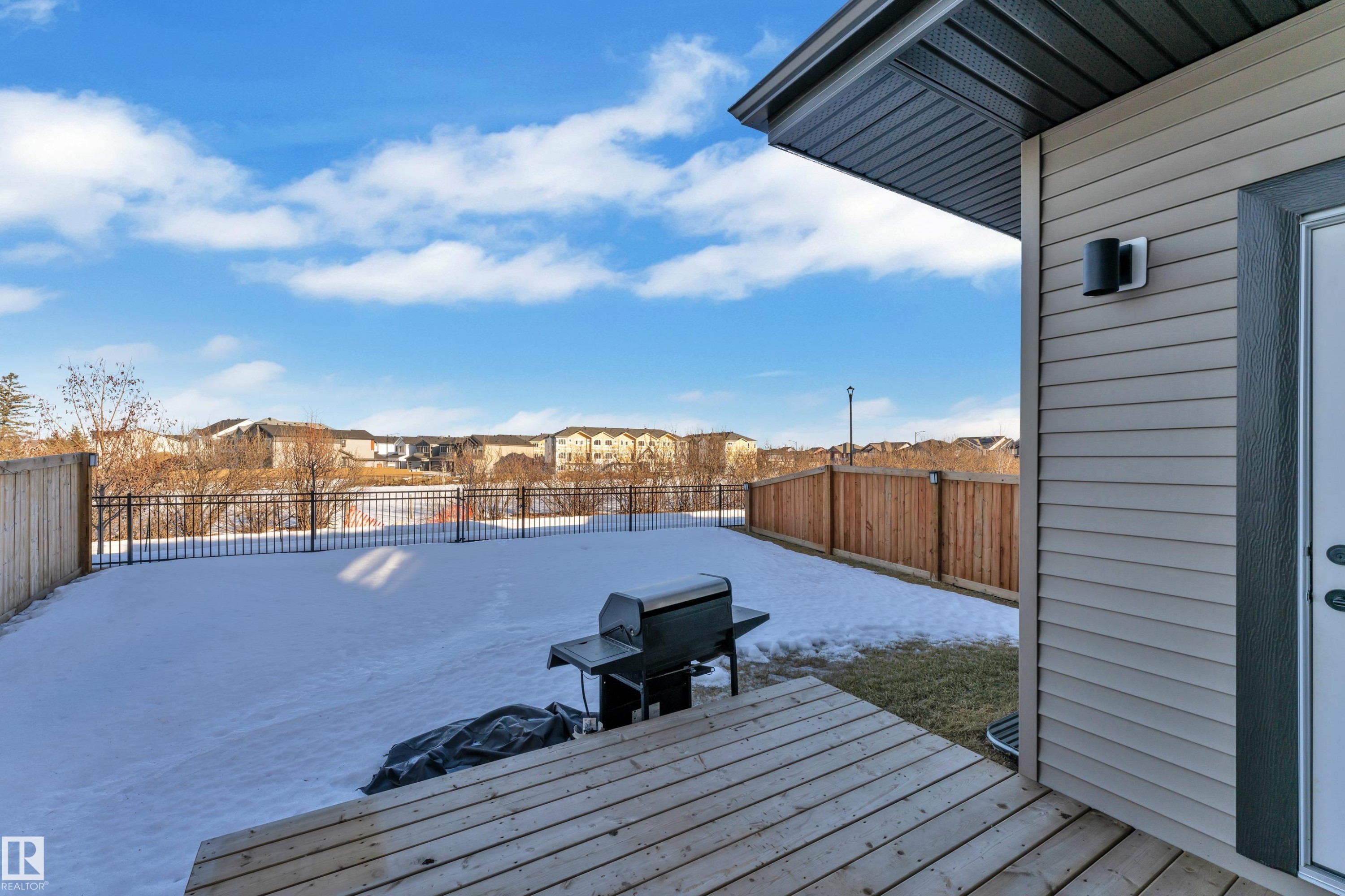 Wooden deck with a residential view, a grill, a fenced backyard, and a patio - 1822 Collip View, Edmonton, AB