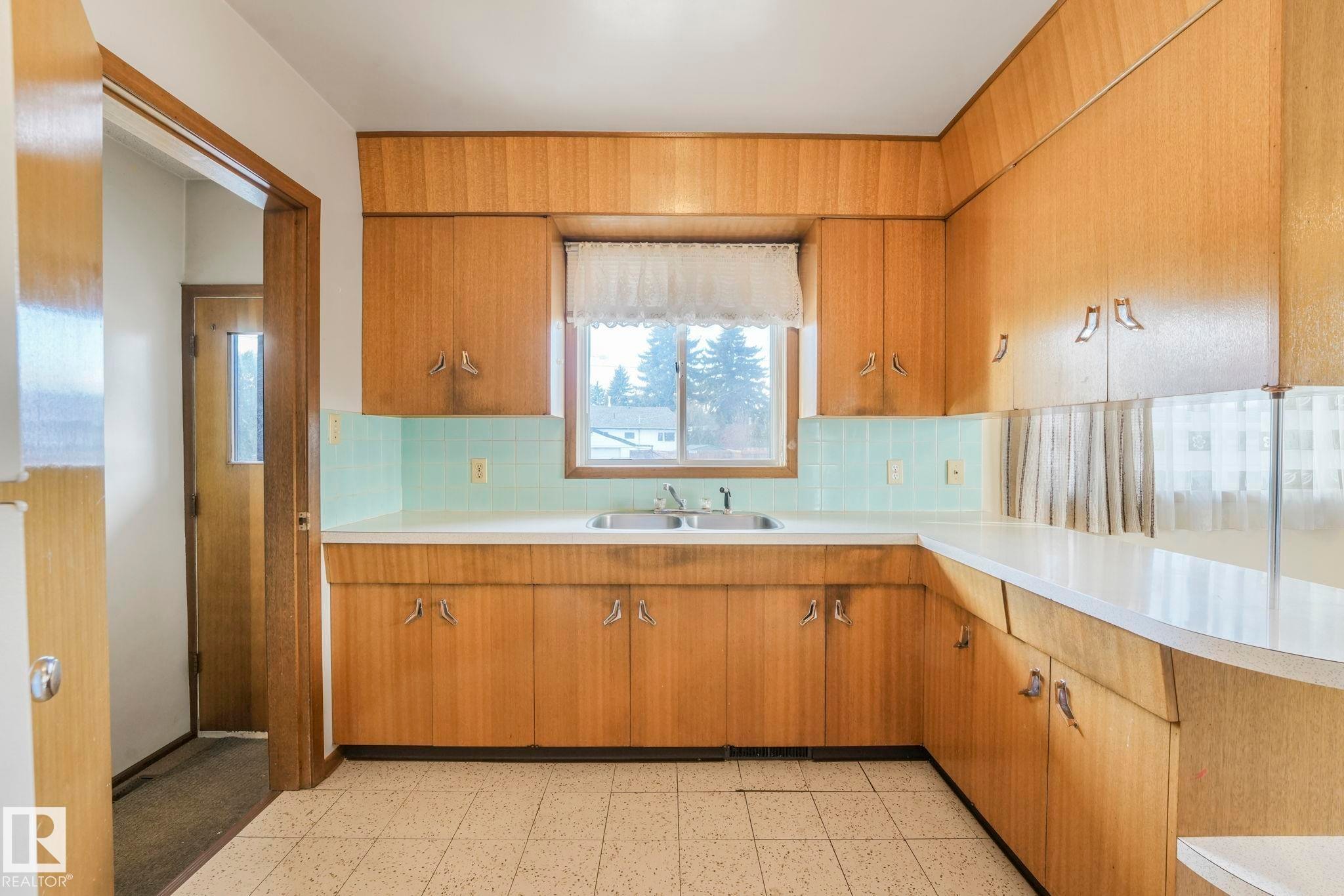 Kitchen featuring wood finish cabinetry, decorative backsplash, and light countertops - 10324 42 Street, Edmonton, AB - Indoor Photo Showing Kitchen