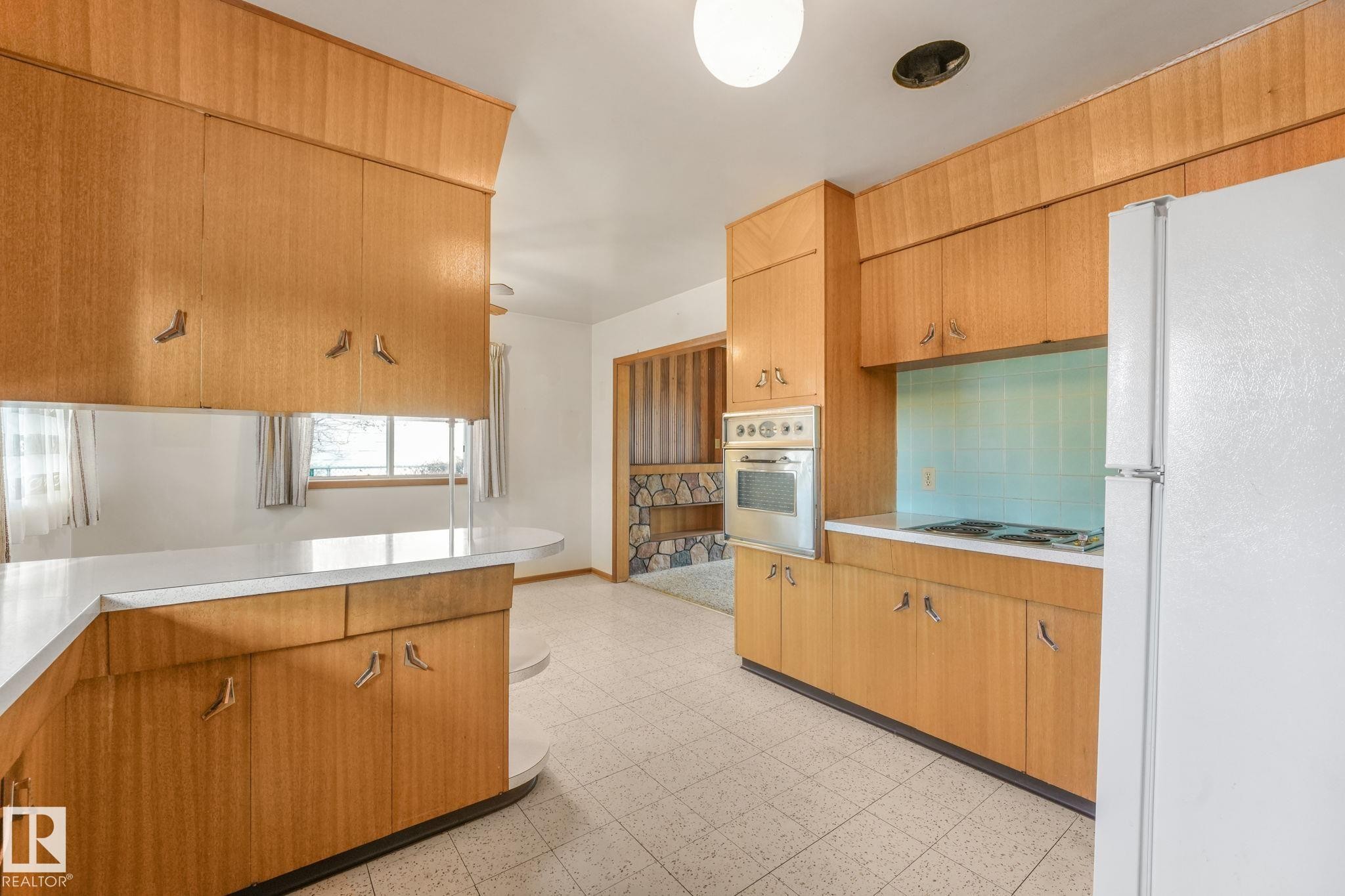 Kitchen featuring freestanding refrigerator, light flooring, light countertops, wood finish cabinetry, and stainless steel electric stovetop - 10324 42 Street, Edmonton, AB - Indoor Photo Showing Kitchen