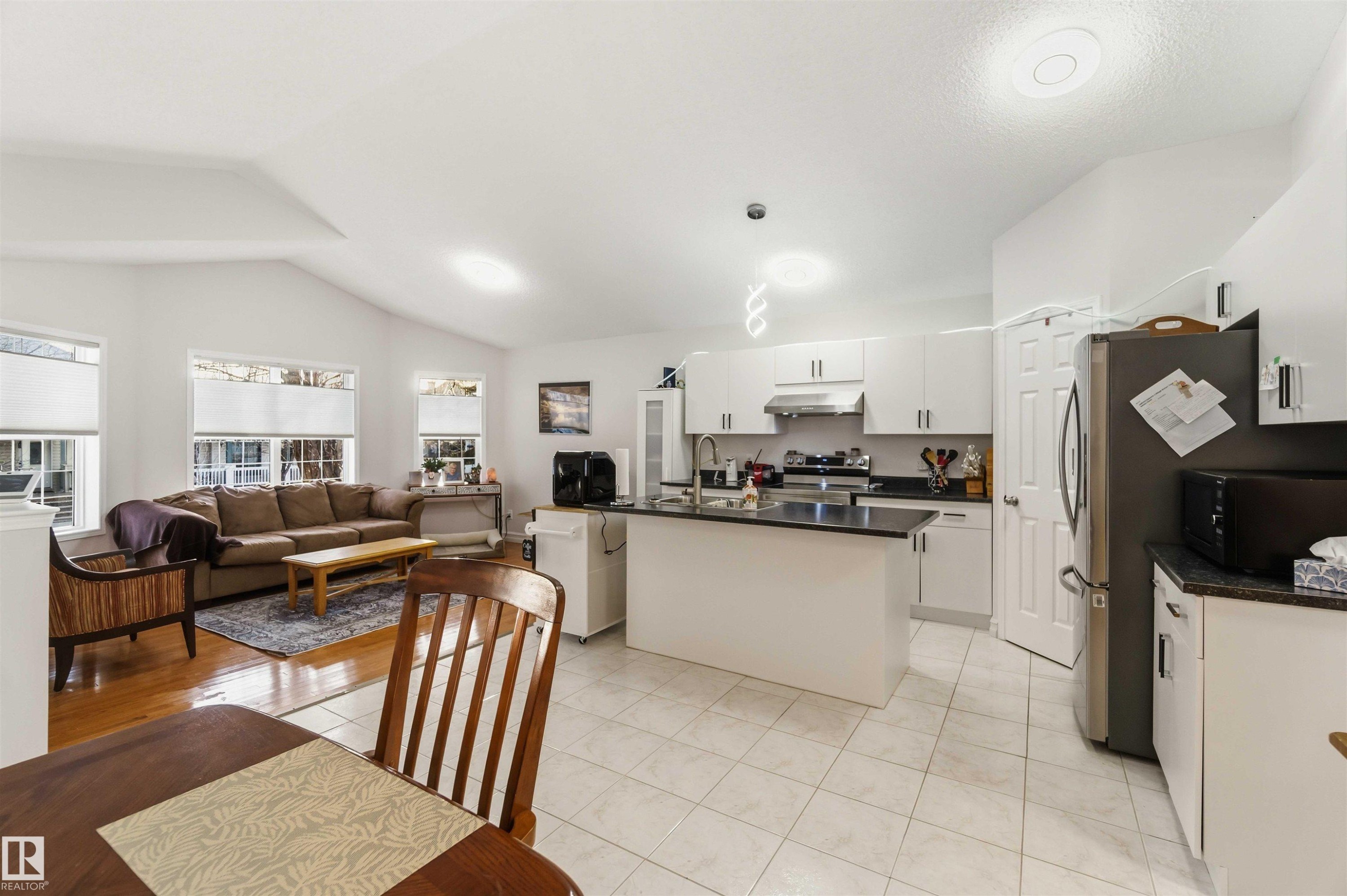 Kitchen featuring open floor plan, black microwave, an island with sink, white cabinetry, and electric range - 1706 Turvey Bend, Edmonton, AB - Indoor