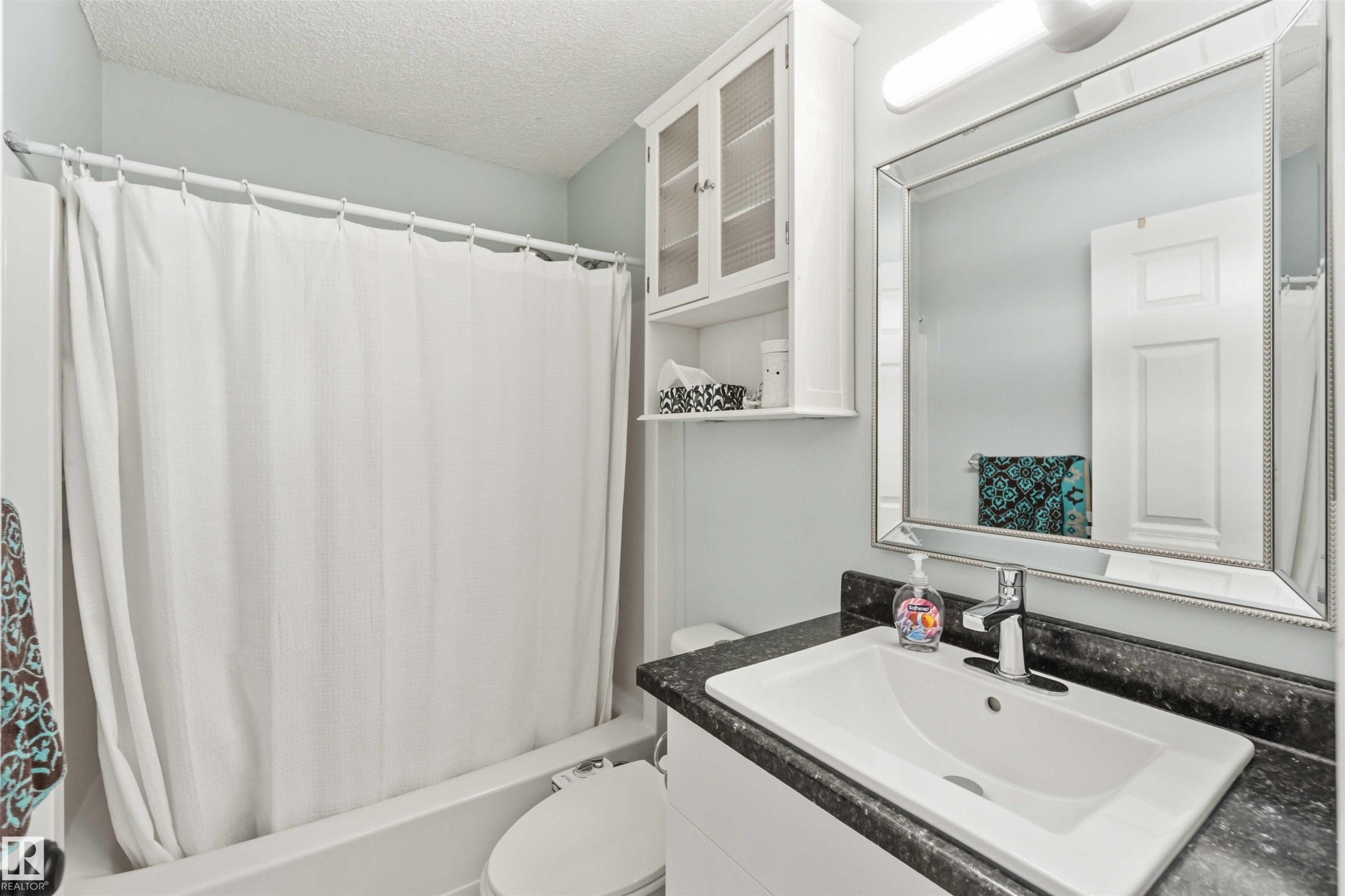 Bathroom featuring vanity, a textured ceiling, and shower / bathtub combination with curtain - 1706 Turvey Bend, Edmonton, AB - Indoor Photo Showing Bathroom