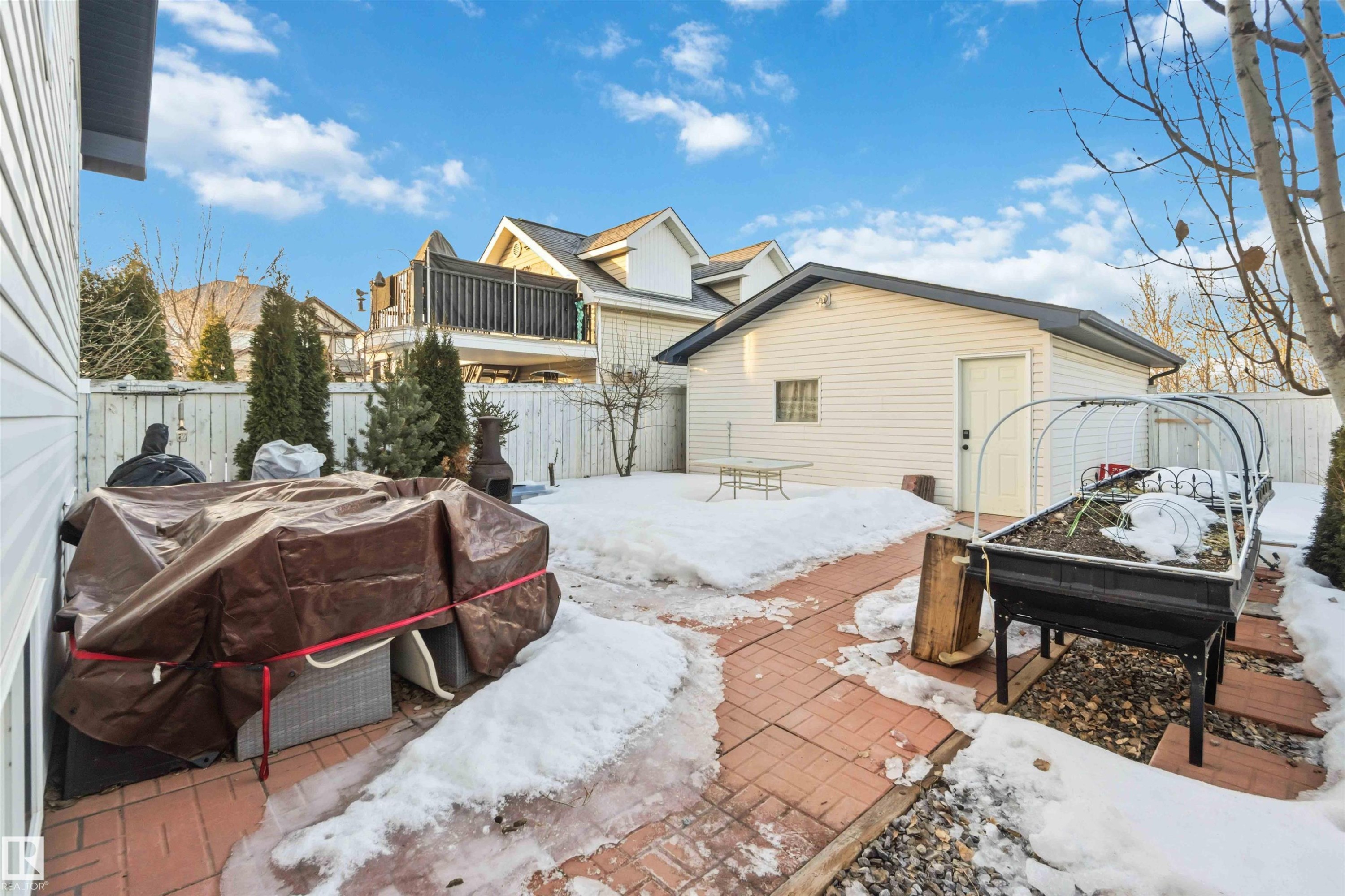 View of snow covered exterior featuring a fenced backyard, a balcony, and a patio - 1706 Turvey Bend, Edmonton, AB - Outdoor