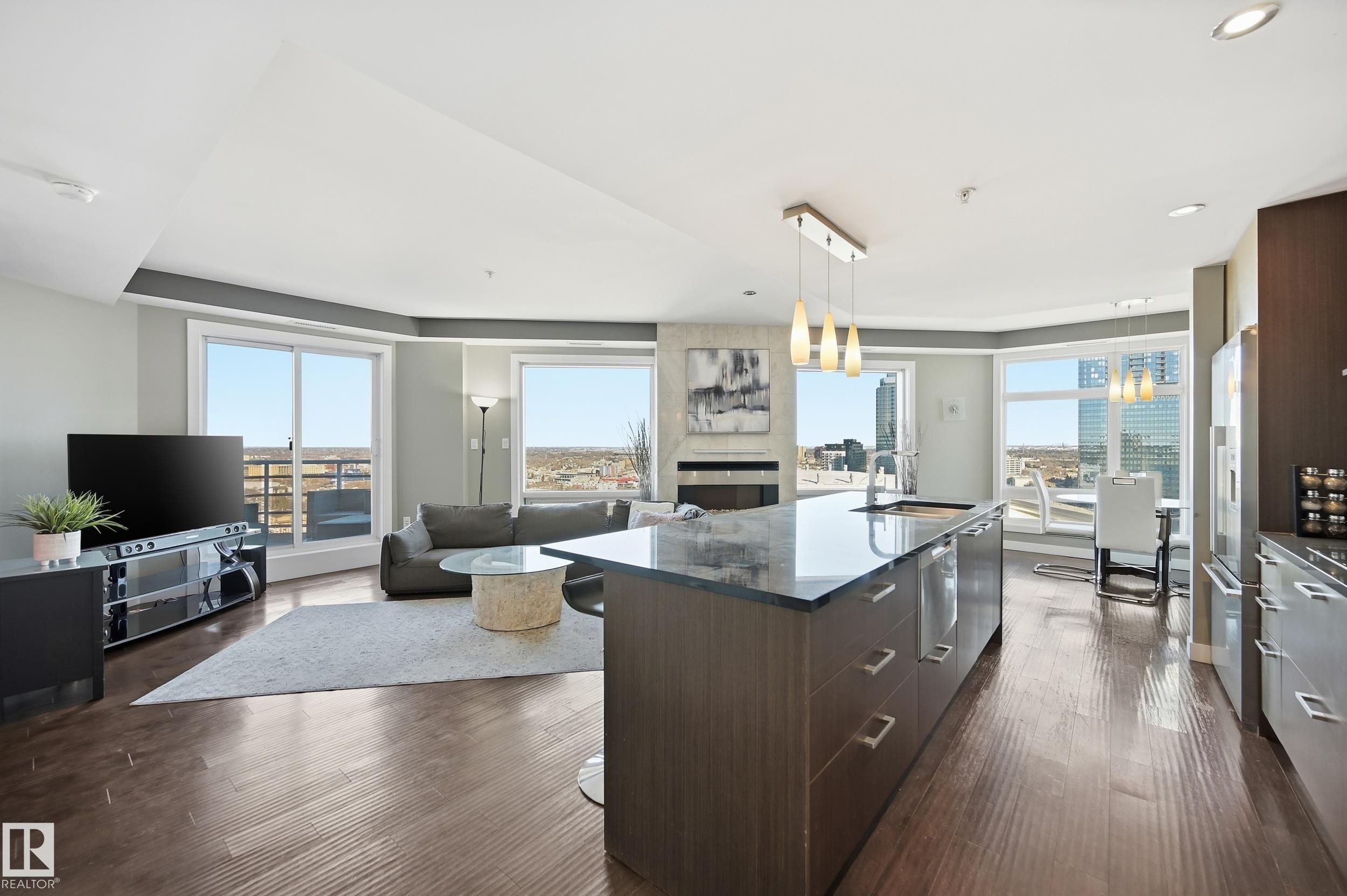Kitchen with modern cabinets, dark wood finish cabinetry, a kitchen breakfast bar, open floor plan, and dark stone counters - 2003 10388 105 Street, Edmonton, AB - Indoor Photo Showing Other Room