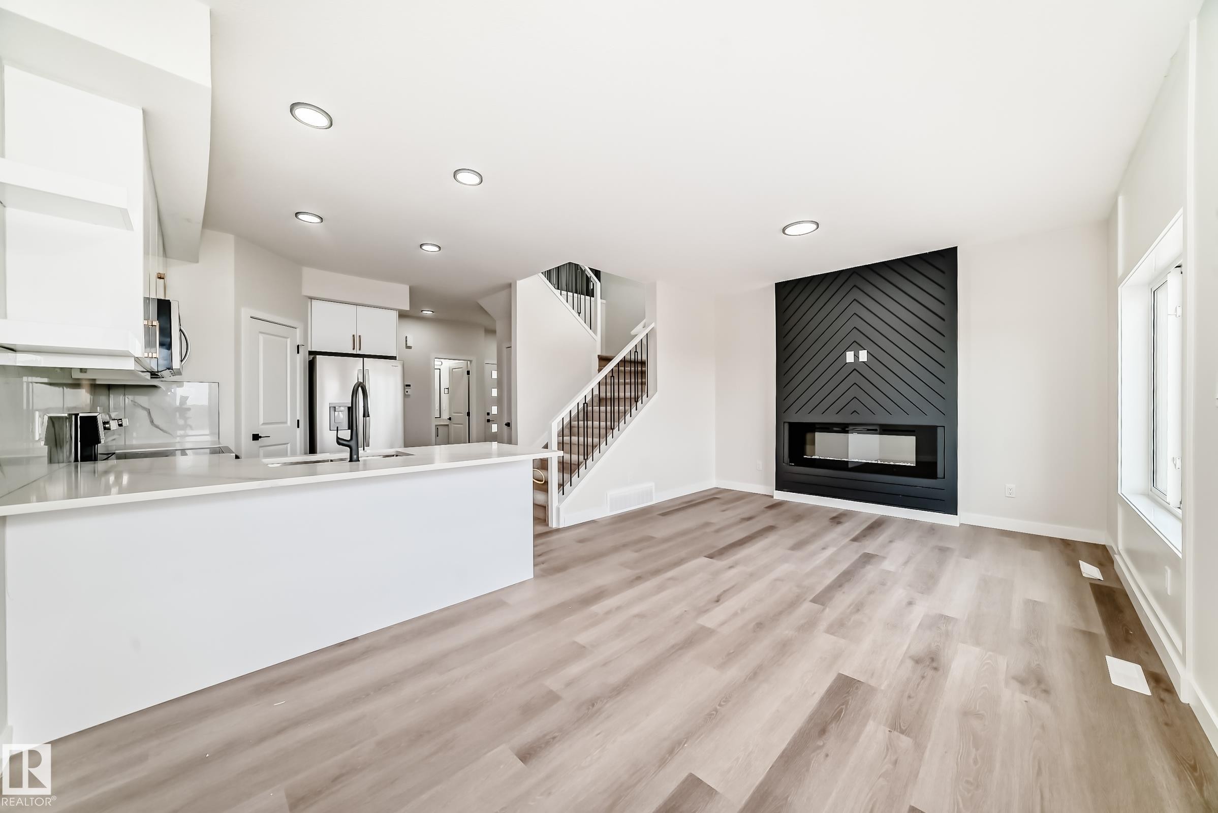 Unfurnished living room featuring a large fireplace, light wood-style floors, and recessed lighting - 135 Pierwyck Loop, Spruce Grove, AB - Indoor With Fireplace