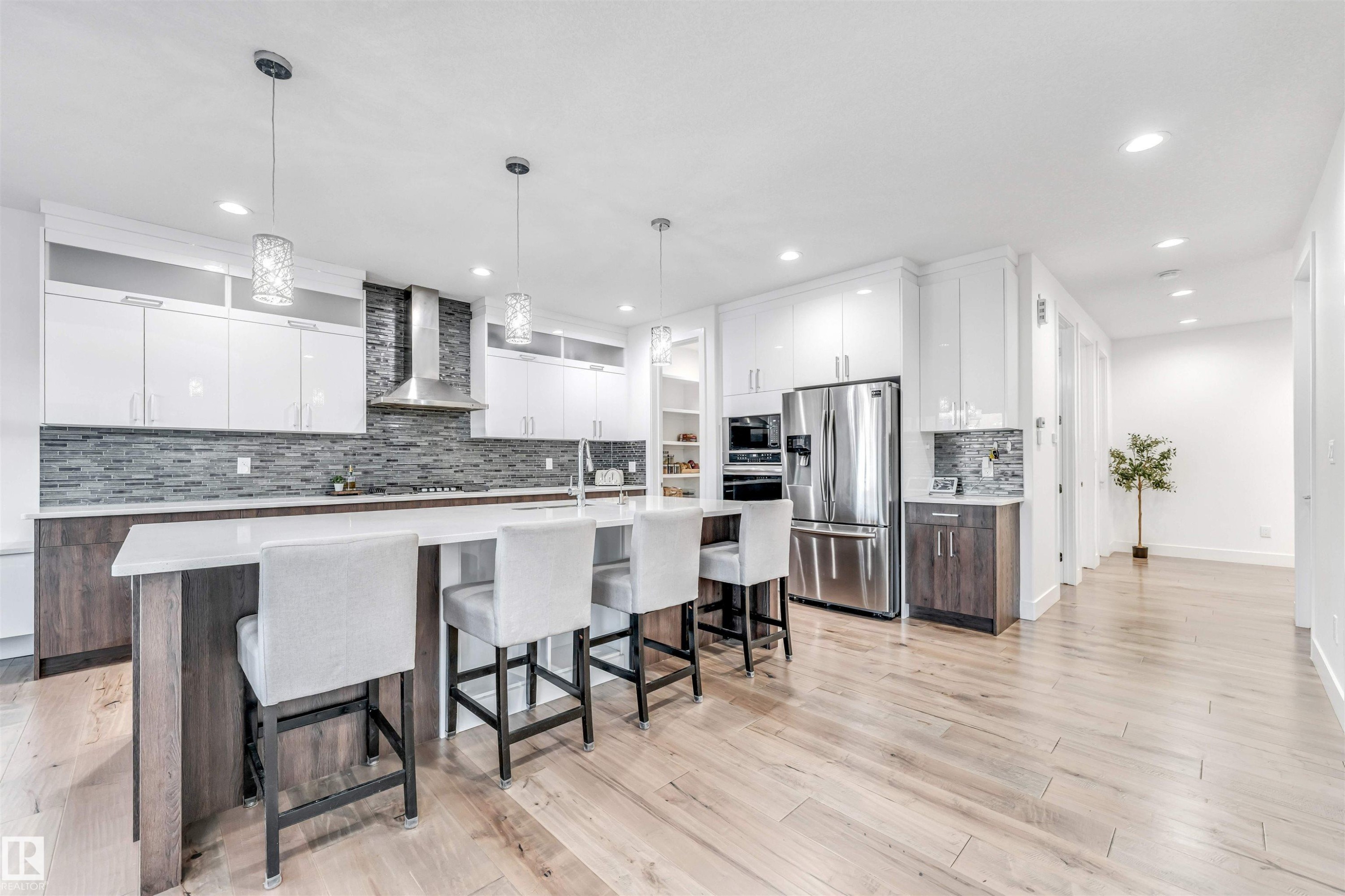 Kitchen with two tone color scheme, a breakfast bar area, stainless steel fridge with ice dispenser, a large island, and decorative backsplash - 1407 Graydon Hill Way, Edmonton, AB - Indoor Photo Showing Kitchen With Upgraded Kitchen