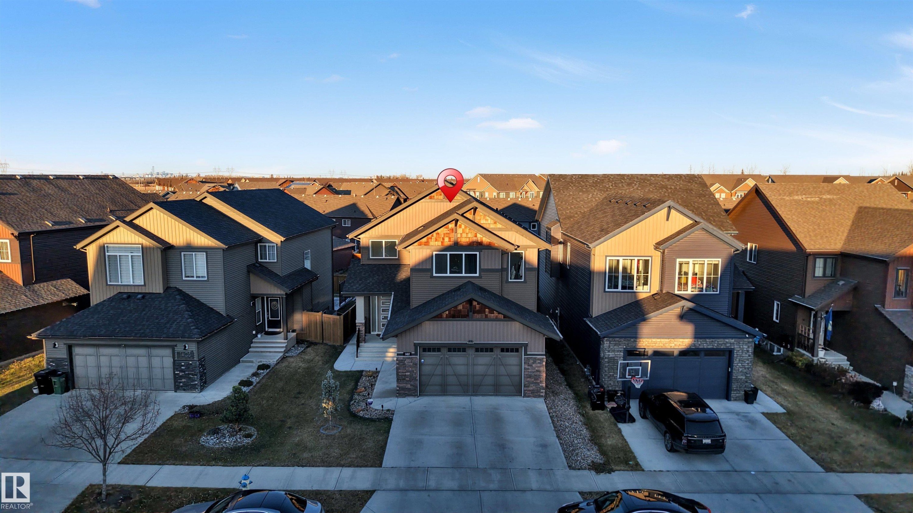 Craftsman-style house featuring stone siding, a residential view, and driveway - 1407 Graydon Hill Way, Edmonton, AB - Outdoor With Facade