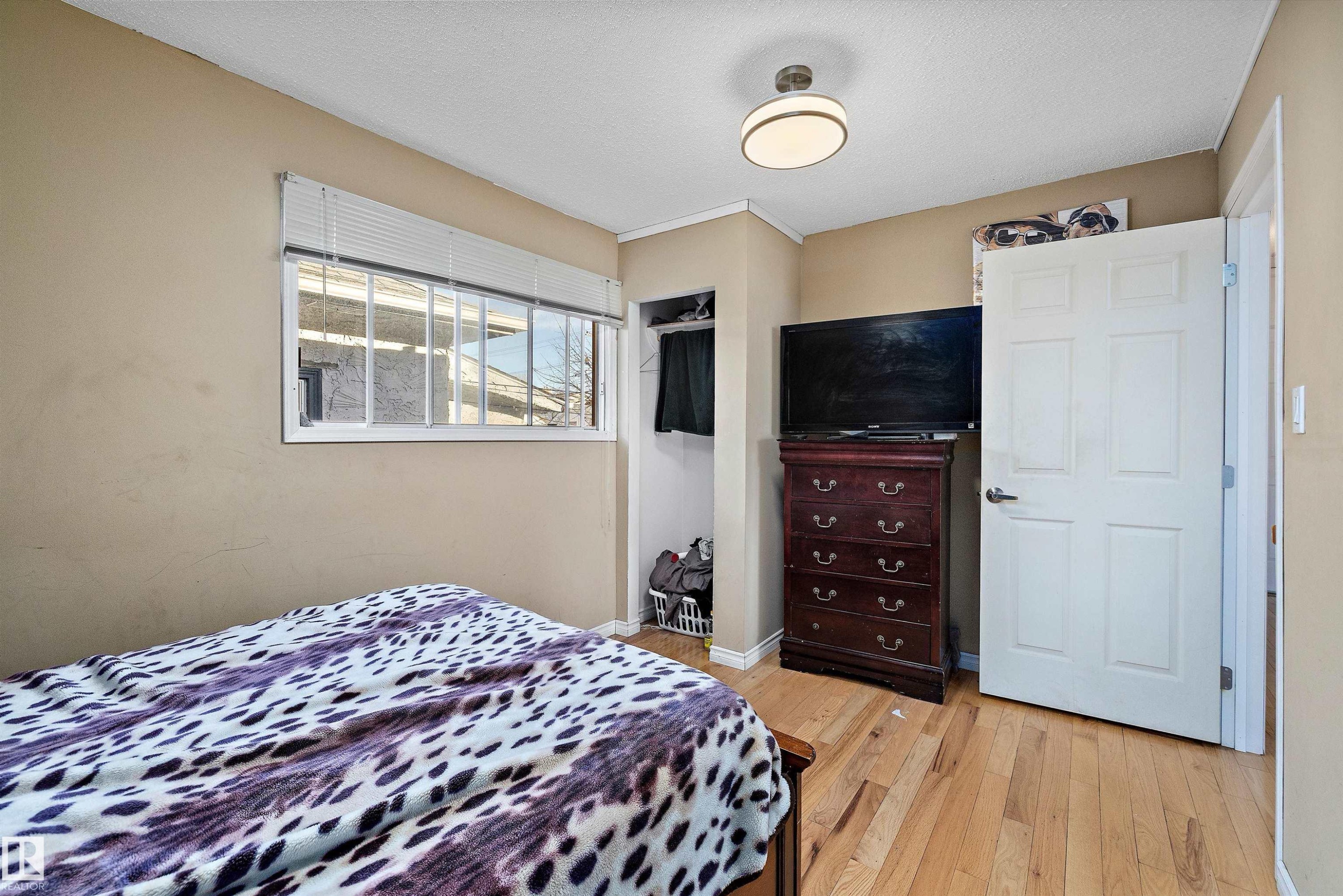 Bedroom with light wood-type flooring, a textured ceiling, and a closet - 12117 91 Street, Edmonton, AB - Indoor Photo Showing Bedroom