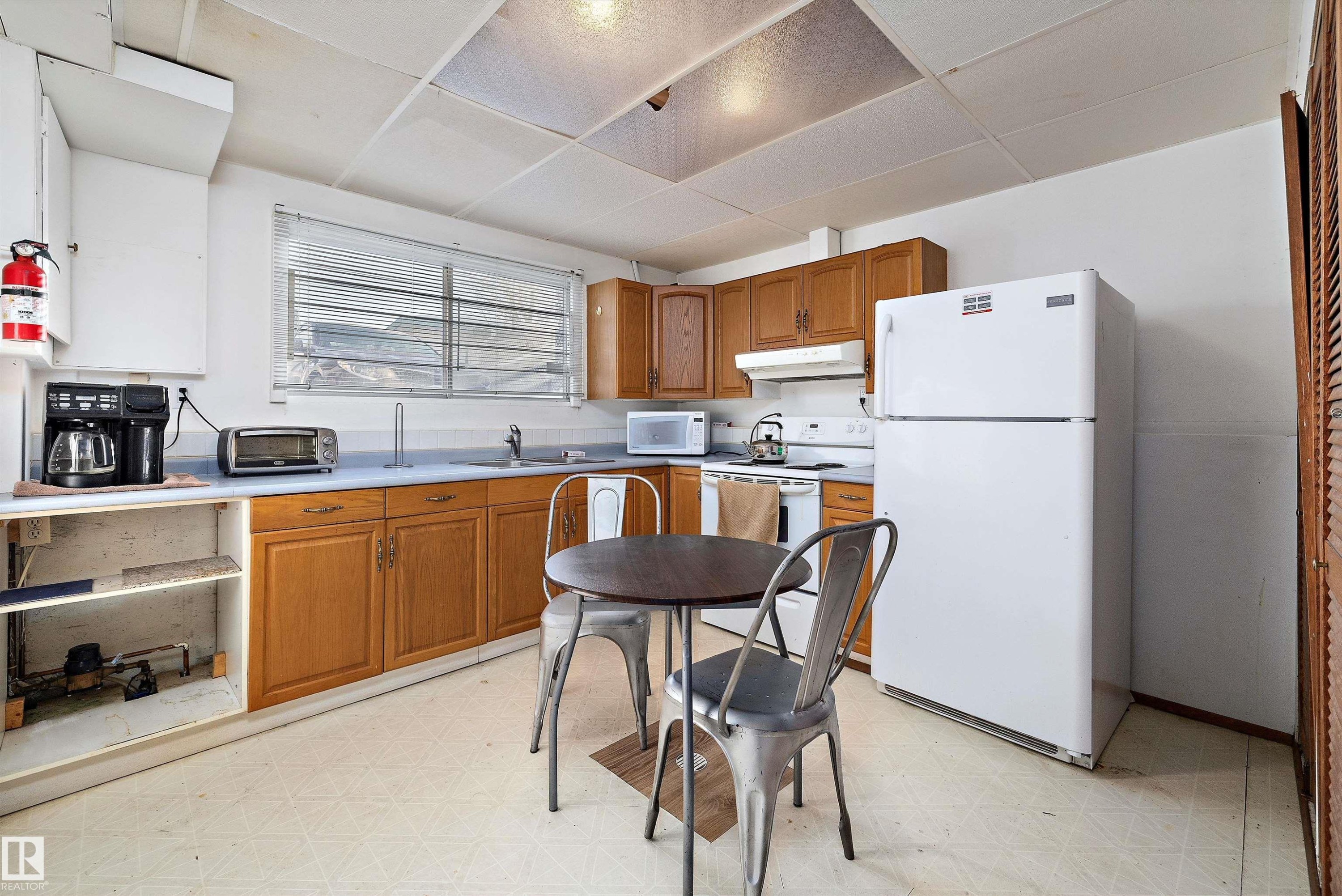 Kitchen with light floors, white appliances, light countertops, wood finish cabinets, and a paneled ceiling - 12117 91 Street, Edmonton, AB - Indoor Photo Showing Kitchen With Double Sink