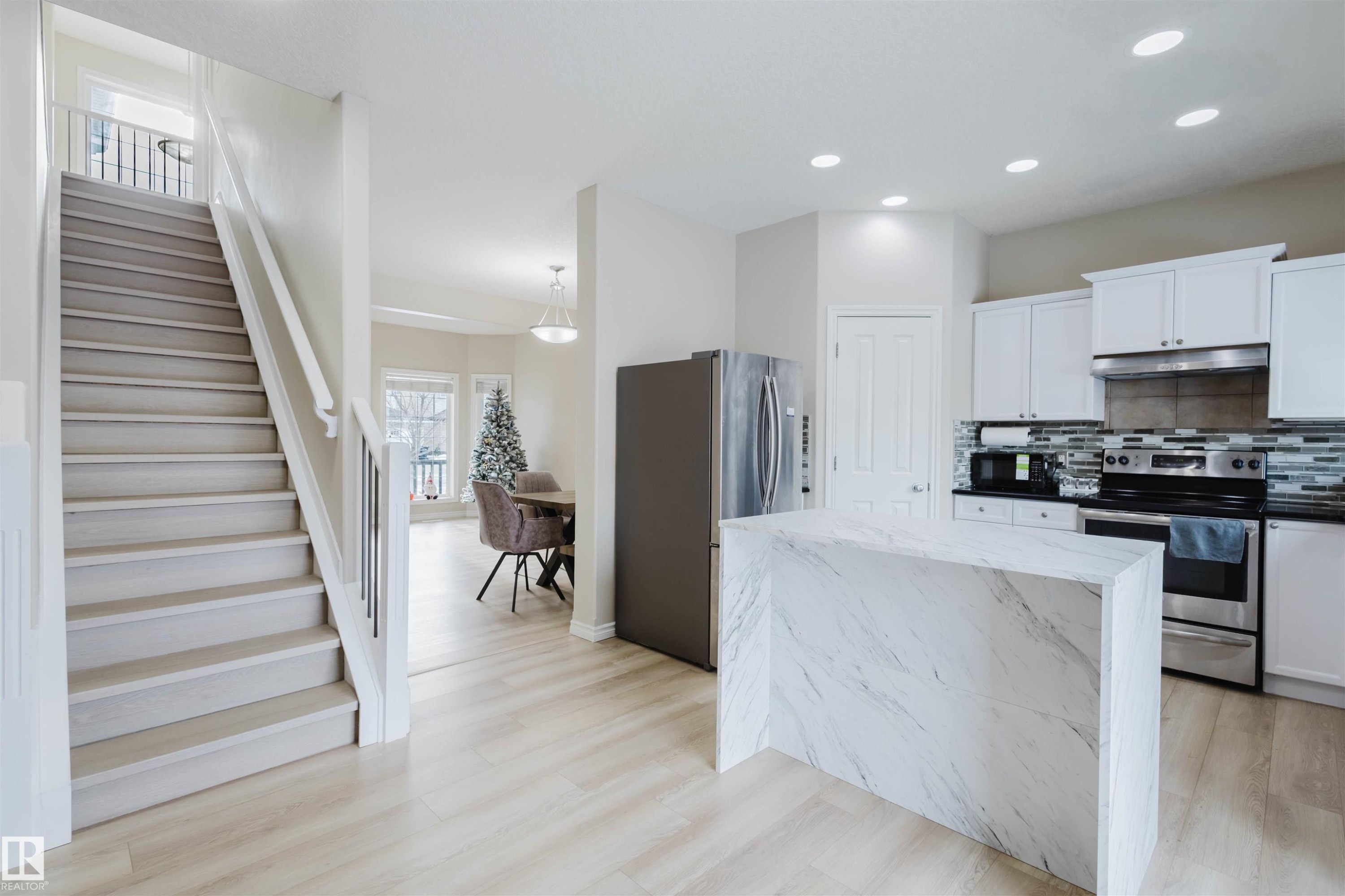 Kitchen with stainless steel appliances, white cabinetry, dark stone counters, light wood finished floors, and recessed lighting - 8420 Sloane Crescent, Edmonton, AB - Indoor Photo Showing Kitchen With Upgraded Kitchen