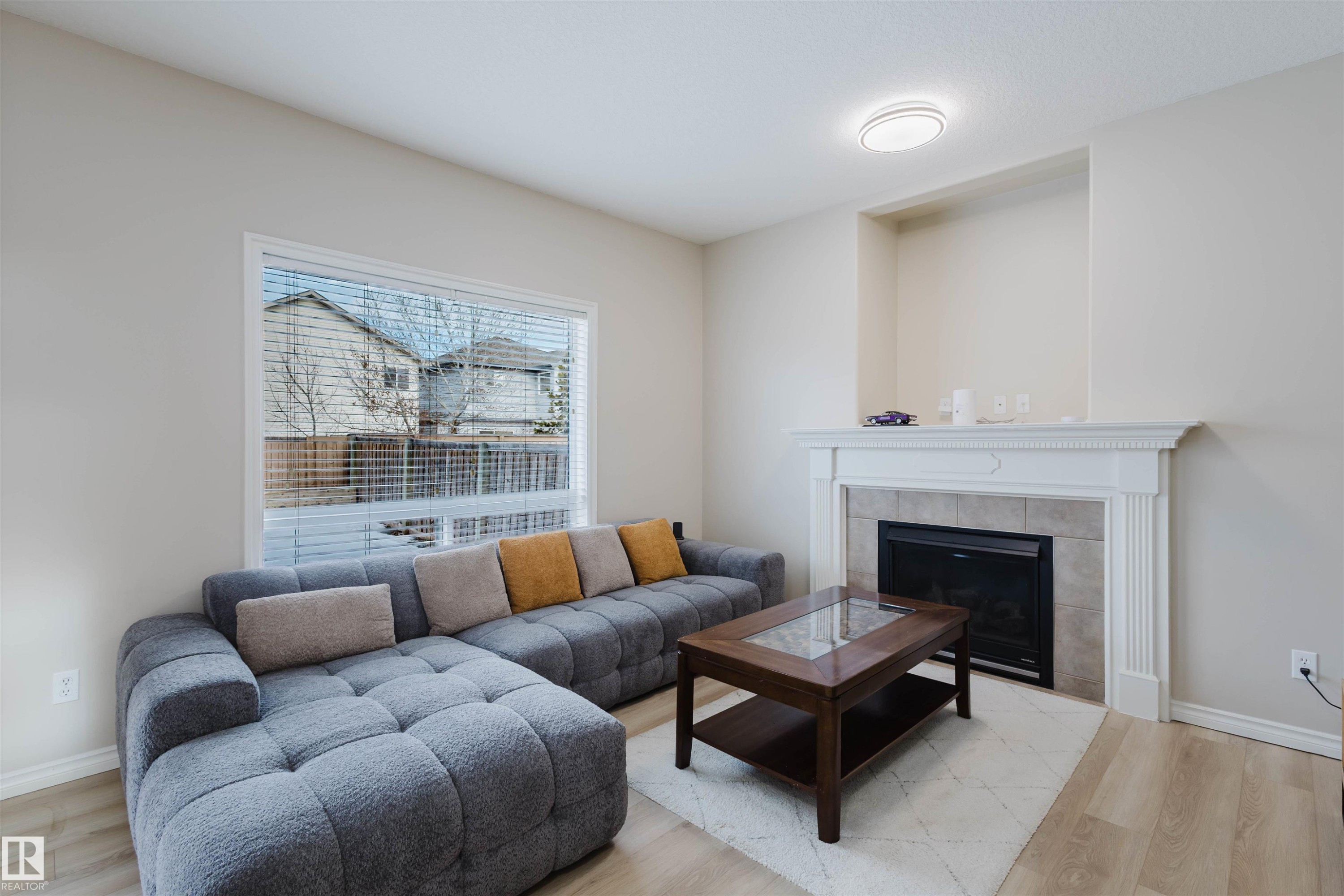 Living area featuring wood finished floors and a tile fireplace - 8420 Sloane Crescent, Edmonton, AB - Indoor Photo Showing Living Room With Fireplace