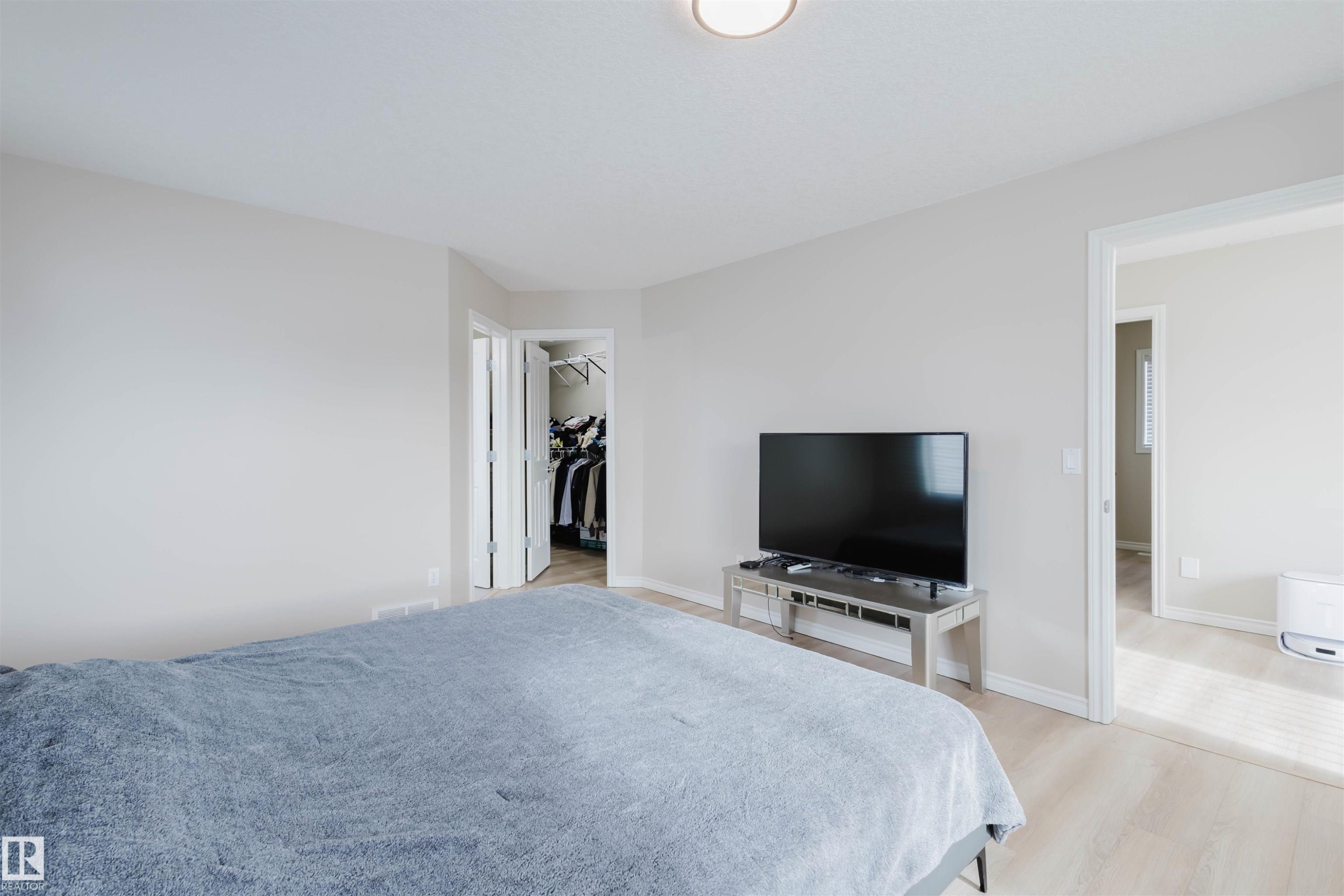 Bedroom with a spacious closet and light wood-type flooring - 8420 Sloane Crescent, Edmonton, AB - Indoor Photo Showing Bedroom