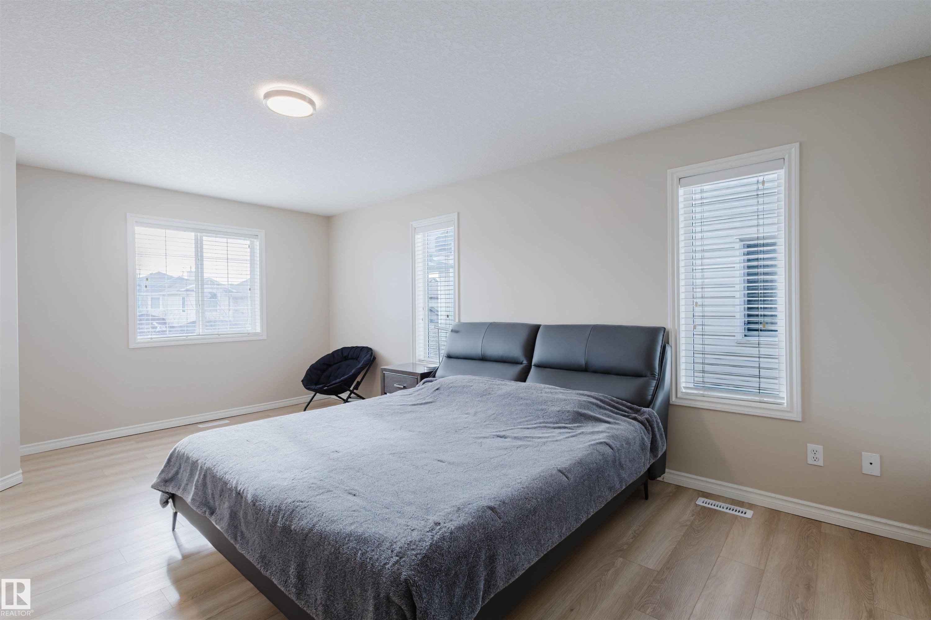 Bedroom featuring light wood-style flooring and multiple windows - 8420 Sloane Crescent, Edmonton, AB - Indoor Photo Showing Bedroom