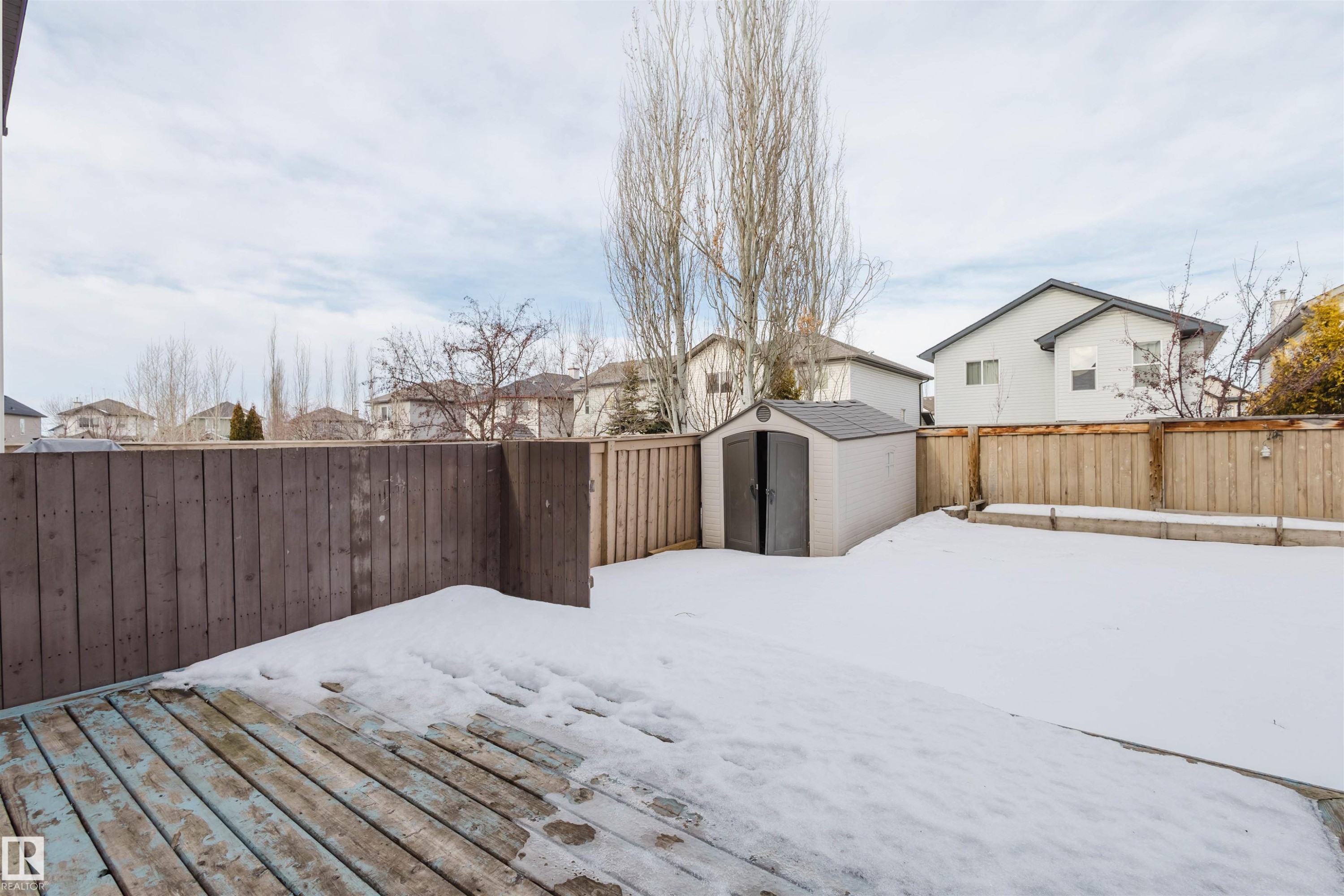 Yard covered in snow featuring a residential view, a shed, a fenced backyard, and a deck - 8420 Sloane Crescent, Edmonton, AB - Outdoor