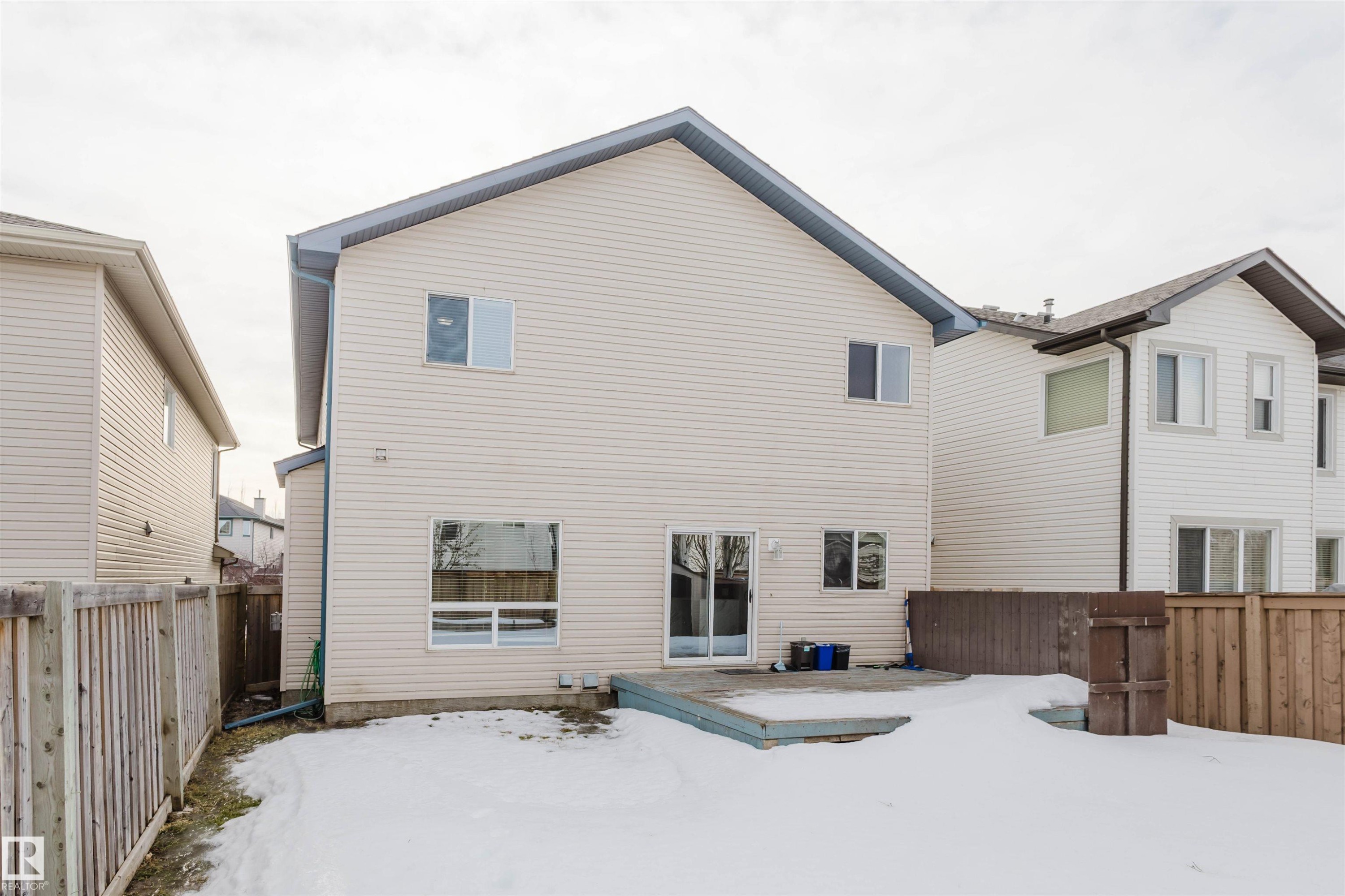 Snow covered rear of property with a fenced backyard and a deck - 8420 Sloane Crescent, Edmonton, AB - Outdoor With Exterior