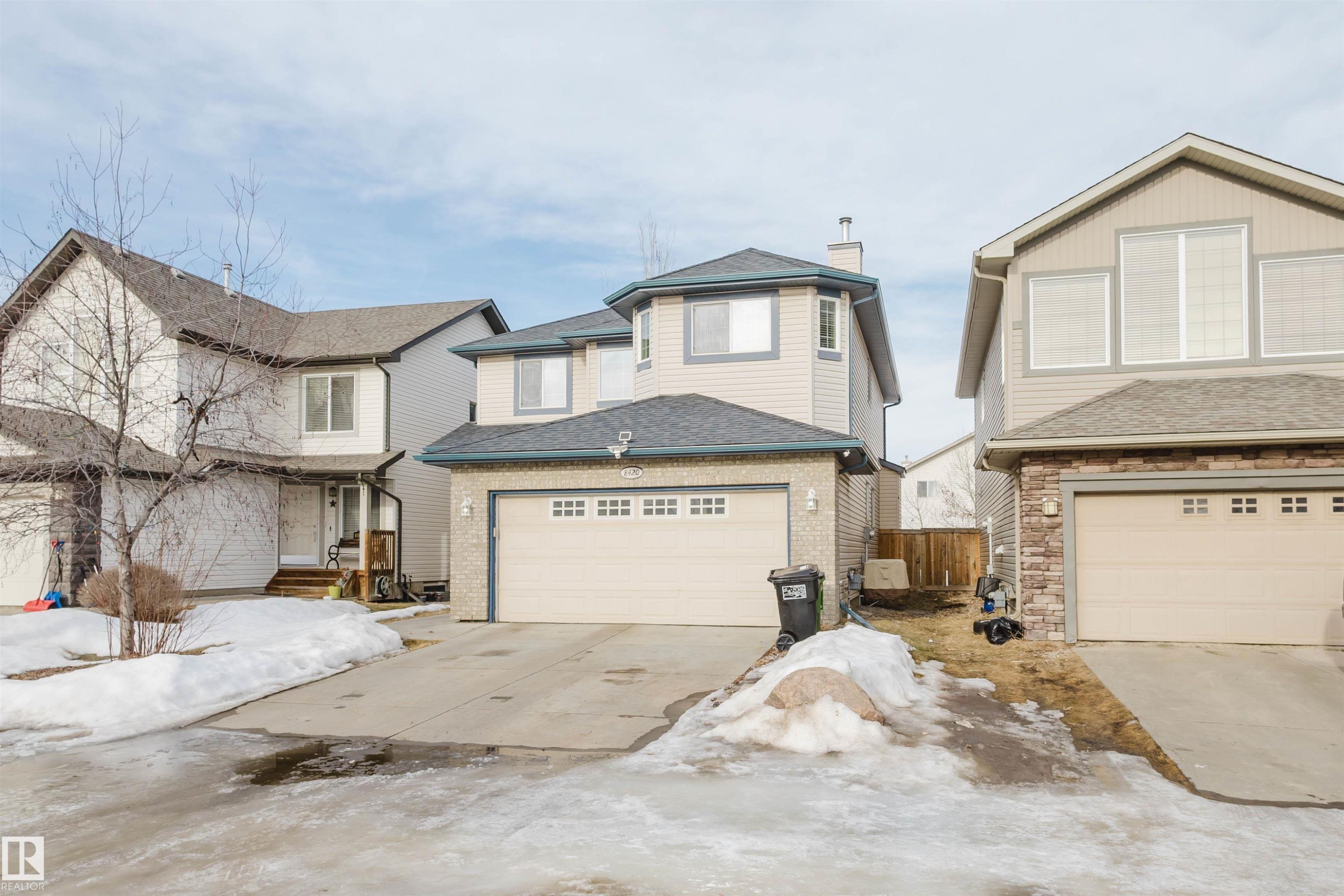 View of front of property with concrete driveway, an attached garage, and a shingled roof - 8420 Sloane Crescent, Edmonton, AB - Outdoor With Facade