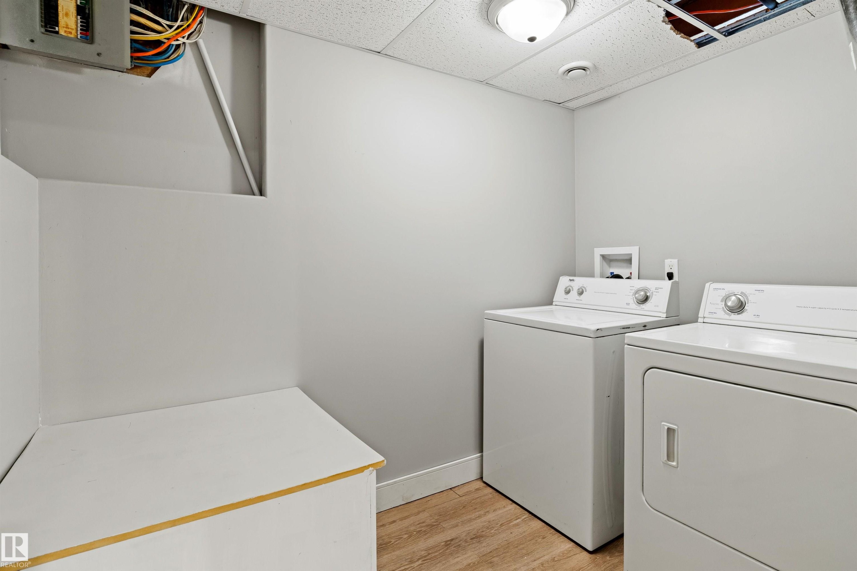Laundry room featuring light wood-type flooring, a paneled ceiling, and washing machine and clothes dryer - 914 9 Street, Cold Lake, AB - Indoor Photo Showing Laundry Room
