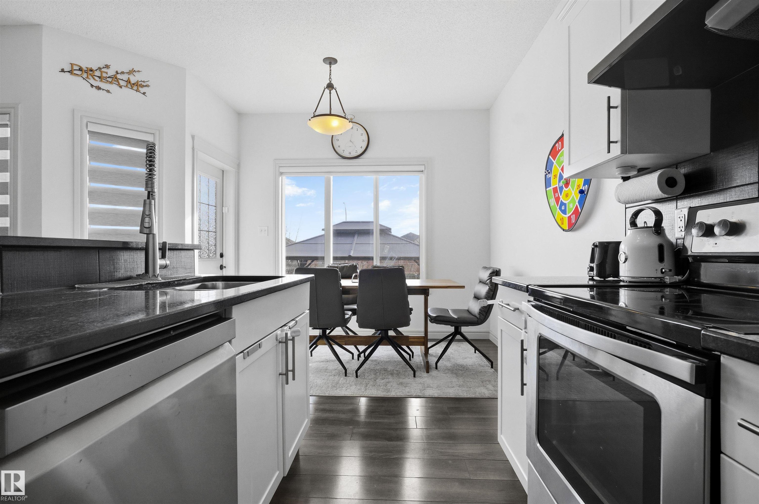 Kitchen featuring stainless steel appliances, white cabinets, range hood, and pendant lighting - 1965 118 Street, Edmonton, AB - Indoor Photo Showing Kitchen With Double Sink