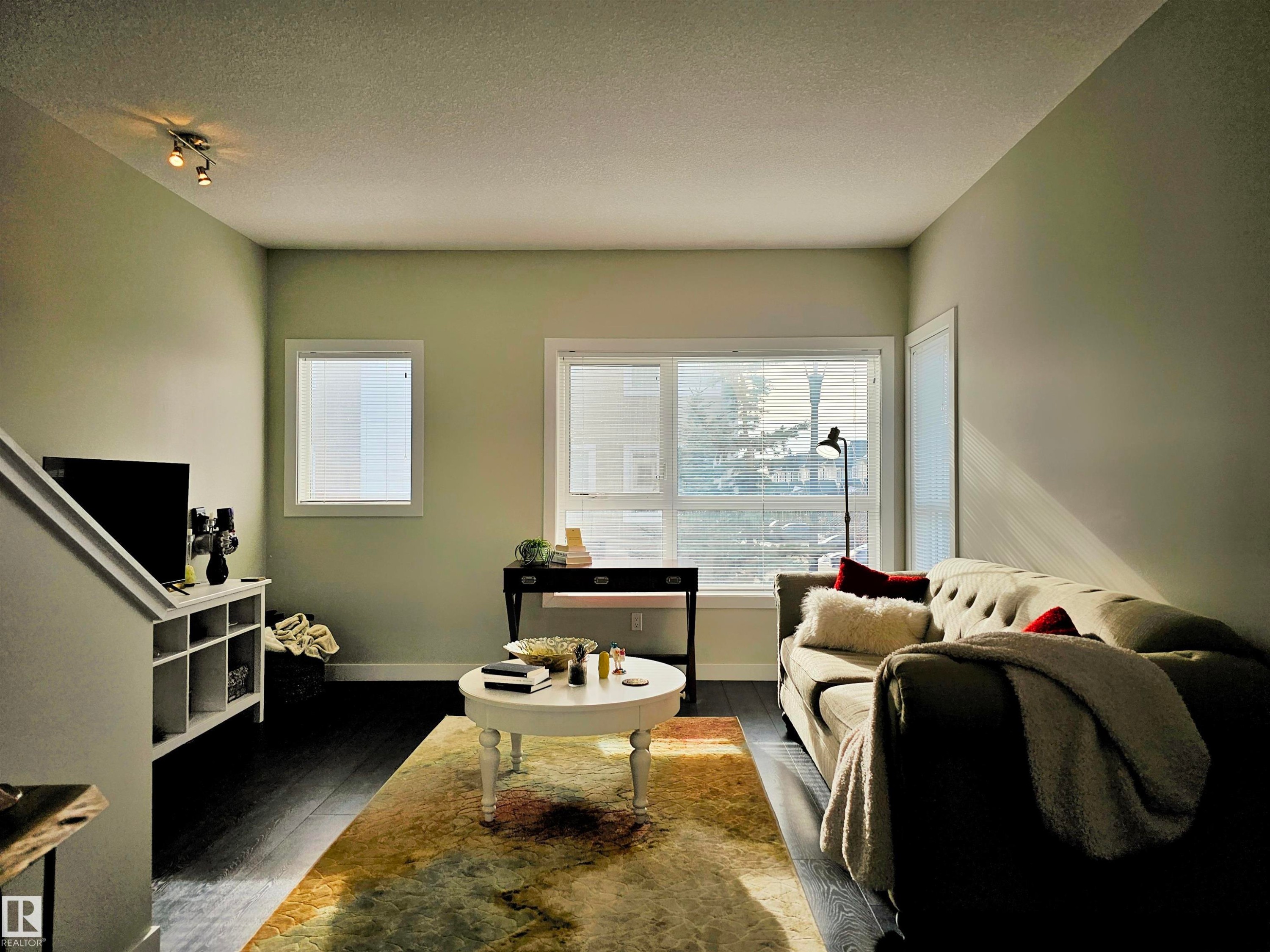 Living room featuring a textured ceiling, wood finished floors, and rail lighting - 129 2560 Pegasus Boulevard, Edmonton, AB - Indoor Photo Showing Living Room