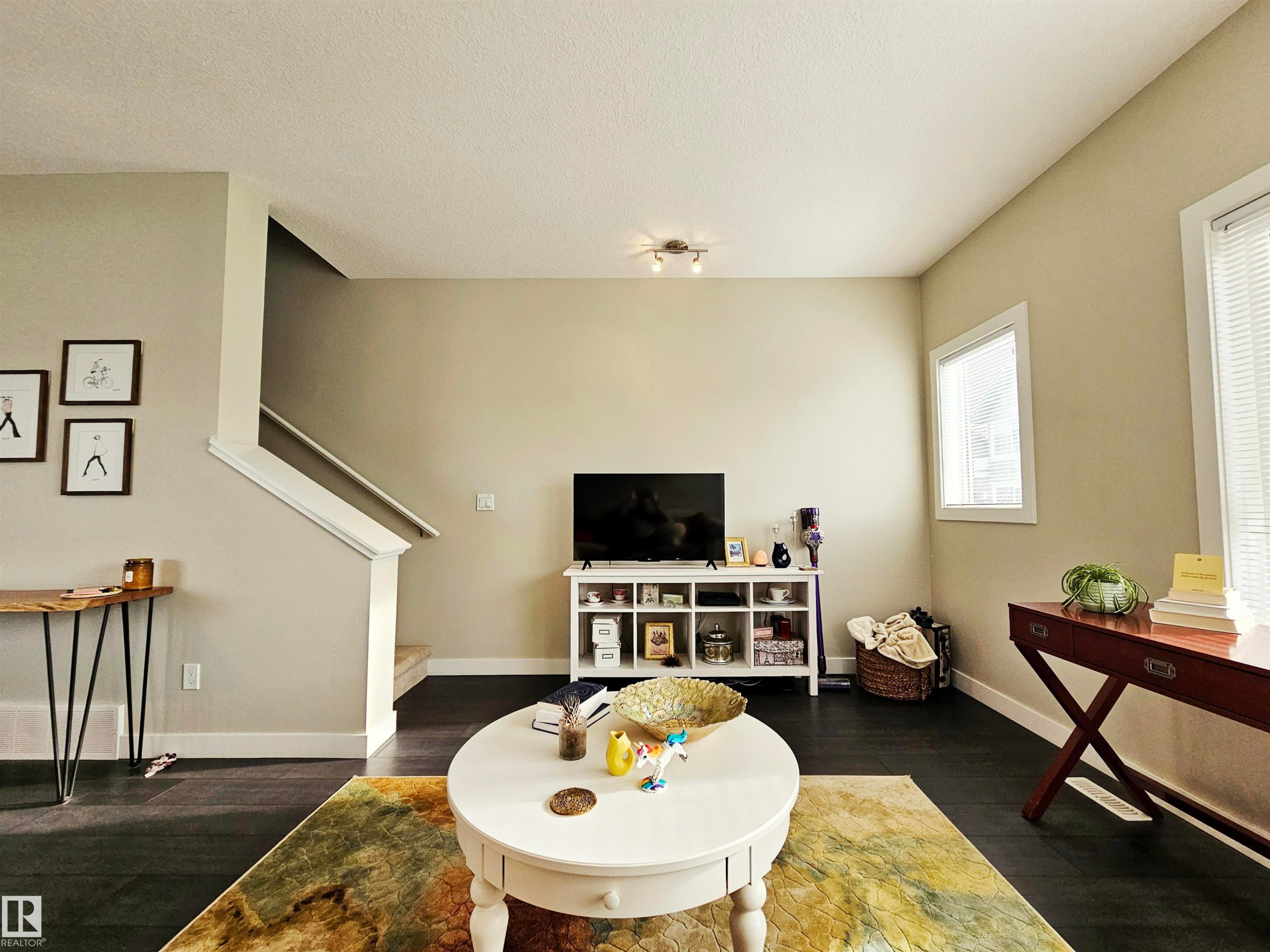 Living room featuring dark wood-type flooring and a textured ceiling - 129 2560 Pegasus Boulevard, Edmonton, AB - Indoor Photo Showing Living Room