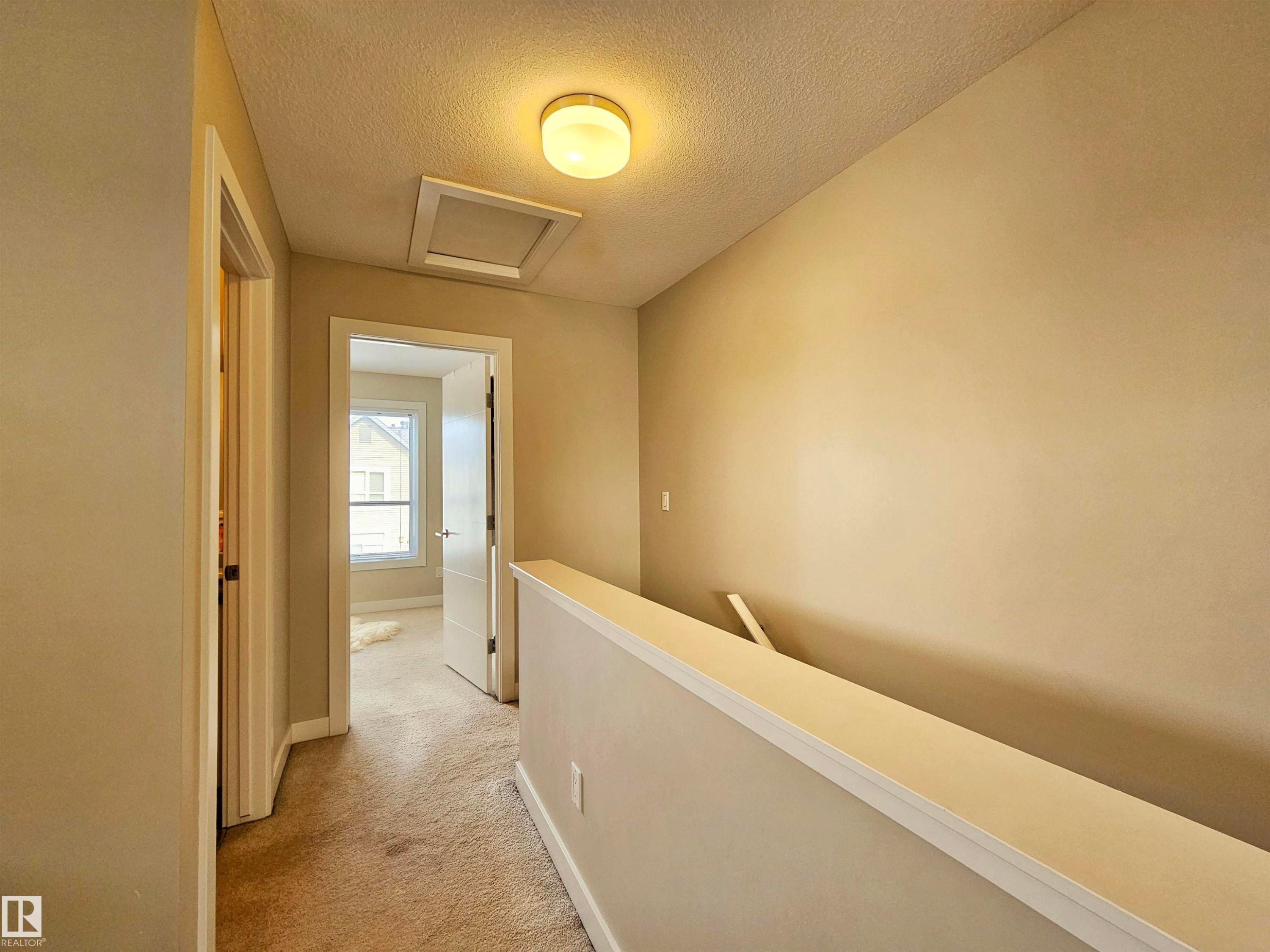 Hall with an upstairs landing, light colored carpet, and a textured ceiling - 129 2560 Pegasus Boulevard, Edmonton, AB - Indoor Photo Showing Other Room