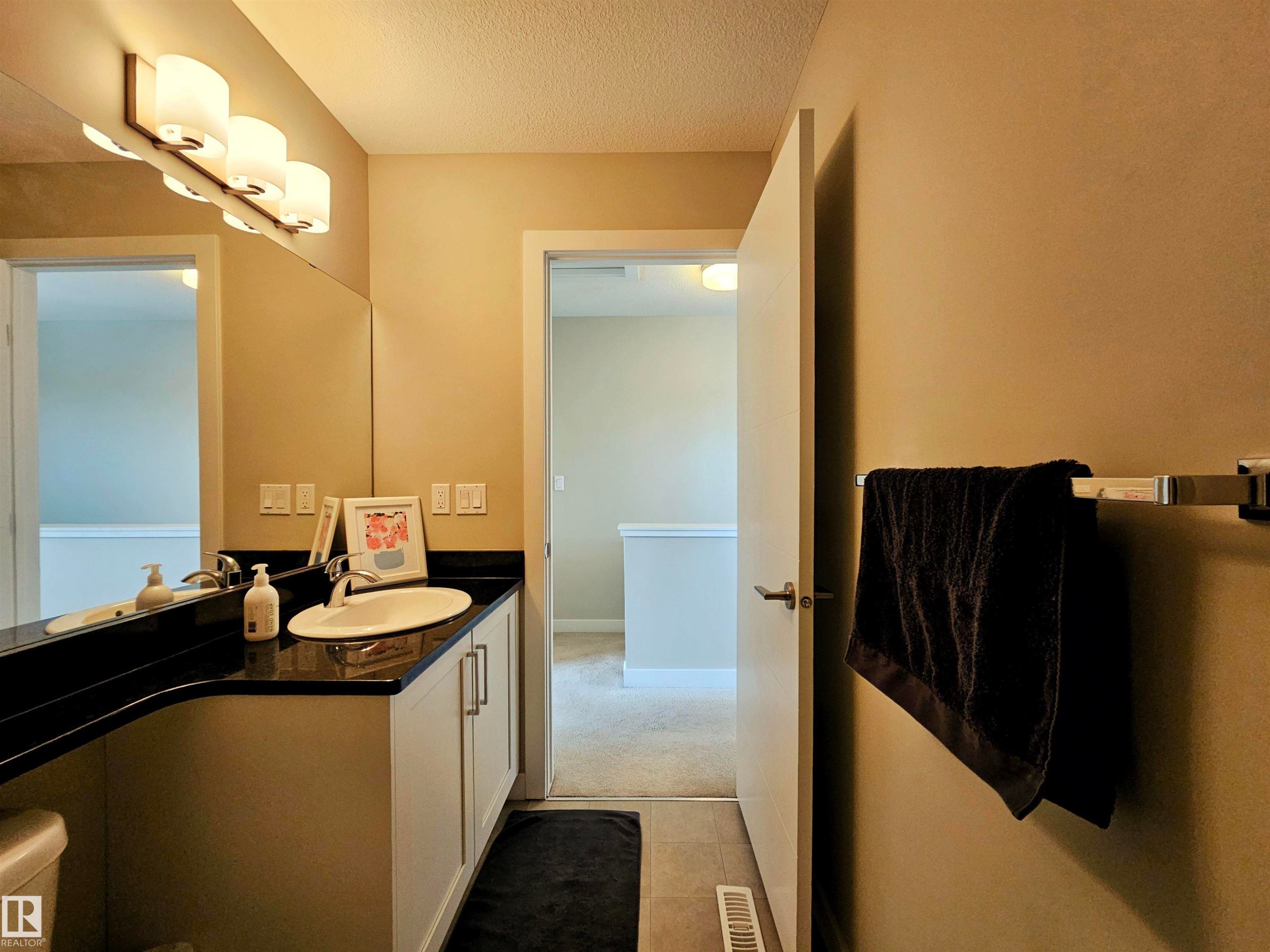 Bathroom with vanity, a textured ceiling, light tile patterned floors, and light carpet - 129 2560 Pegasus Boulevard, Edmonton, AB - Indoor Photo Showing Bathroom