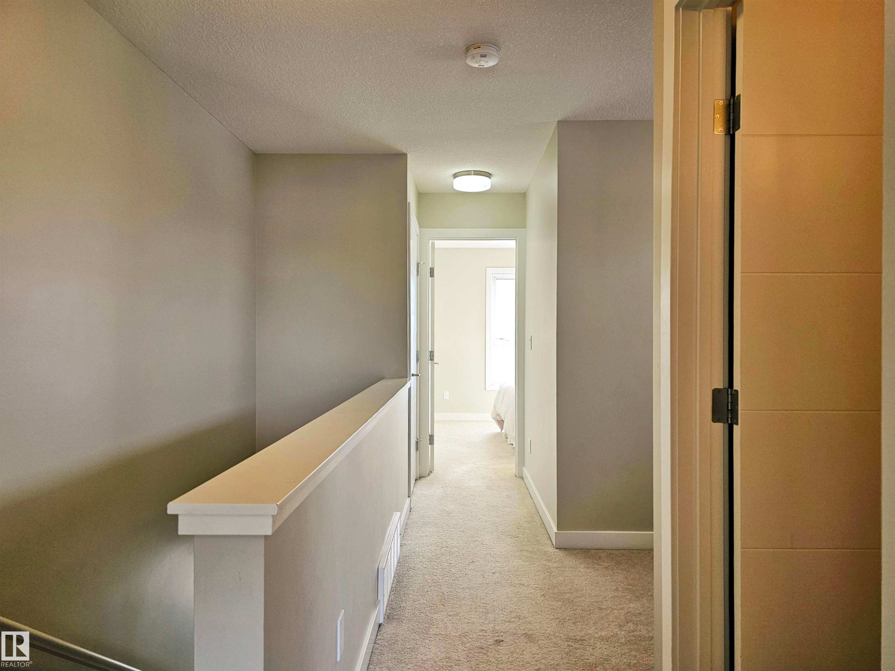 Corridor featuring an upstairs landing, light colored carpet, and a textured ceiling - 129 2560 Pegasus Boulevard, Edmonton, AB - Indoor Photo Showing Other Room