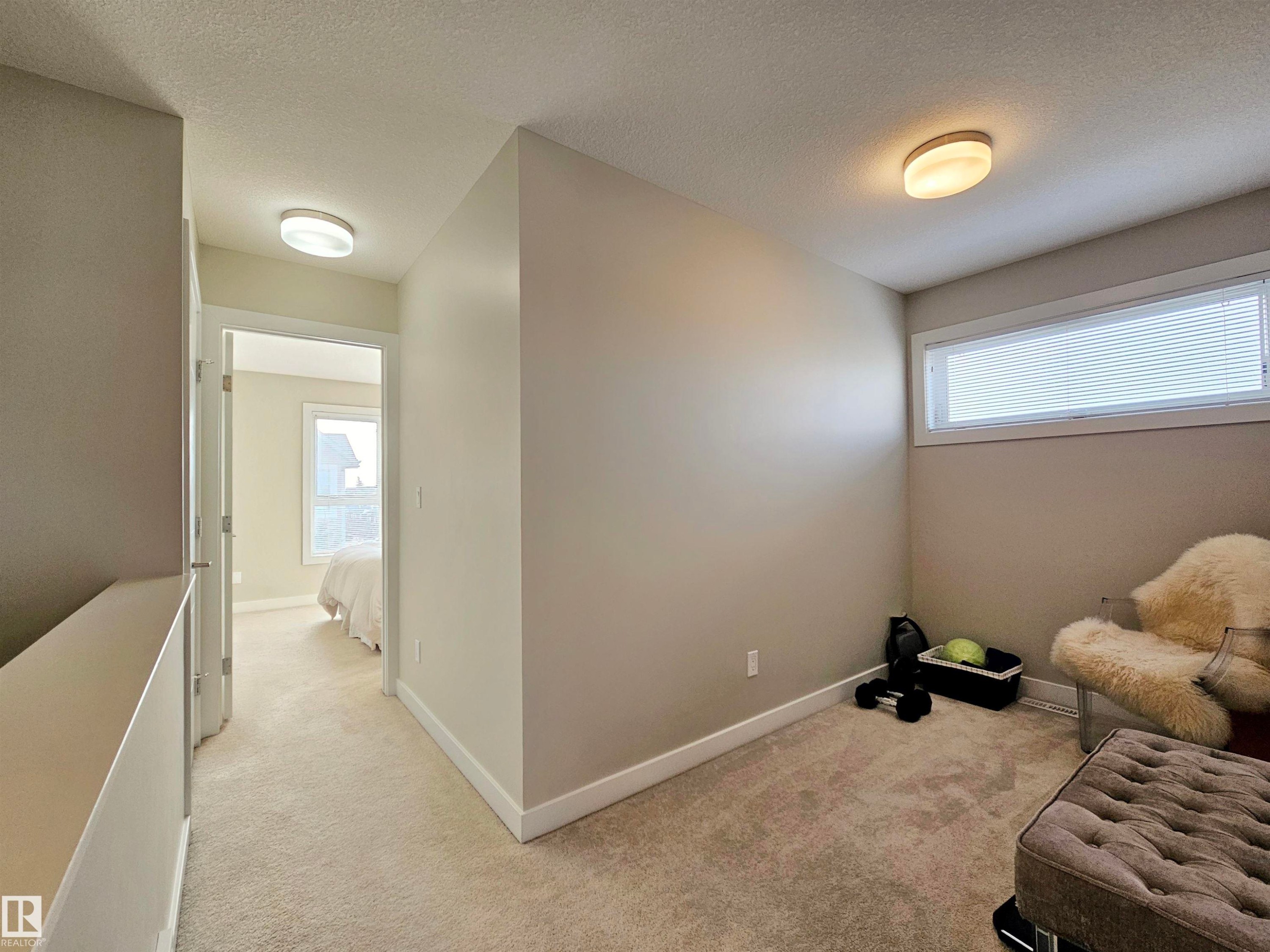 Sitting room with light carpet, a textured ceiling, and plenty of natural light - 129 2560 Pegasus Boulevard, Edmonton, AB - Indoor