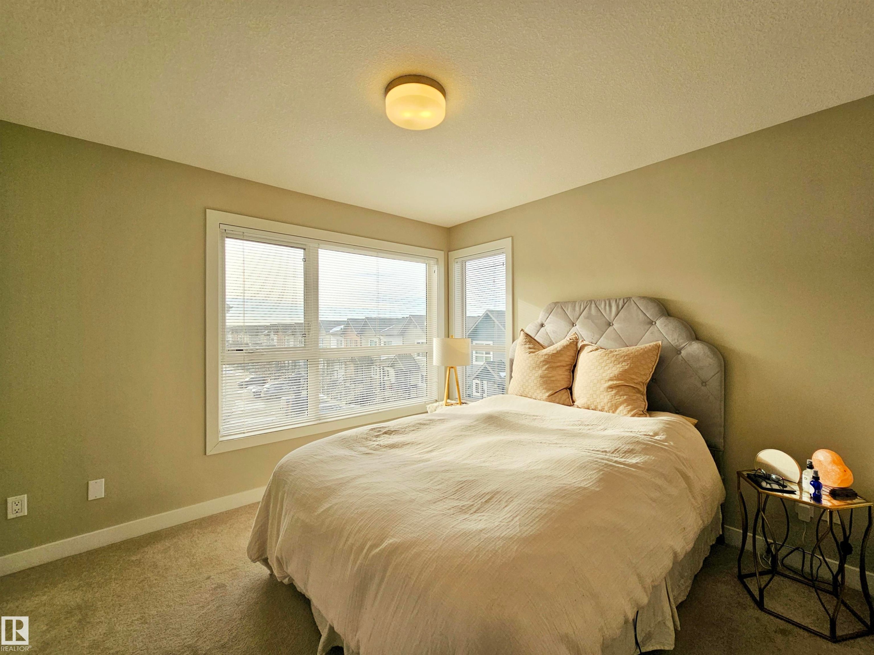 Carpeted bedroom with a textured ceiling and baseboards - 129 2560 Pegasus Boulevard, Edmonton, AB - Indoor Photo Showing Bedroom