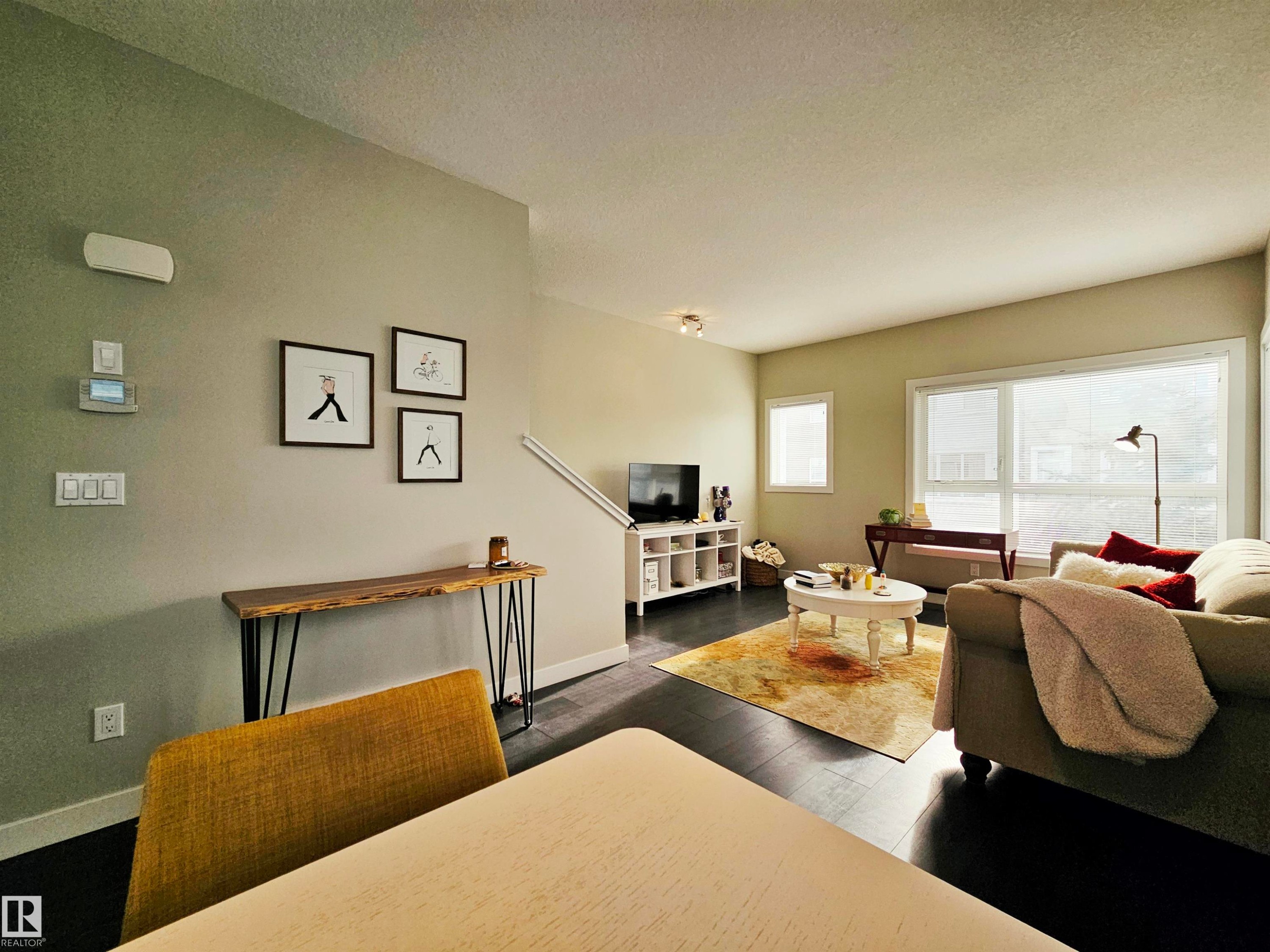 Living room featuring a textured ceiling and dark wood-style floors - 129 2560 Pegasus Boulevard, Edmonton, AB - Indoor Photo Showing Living Room