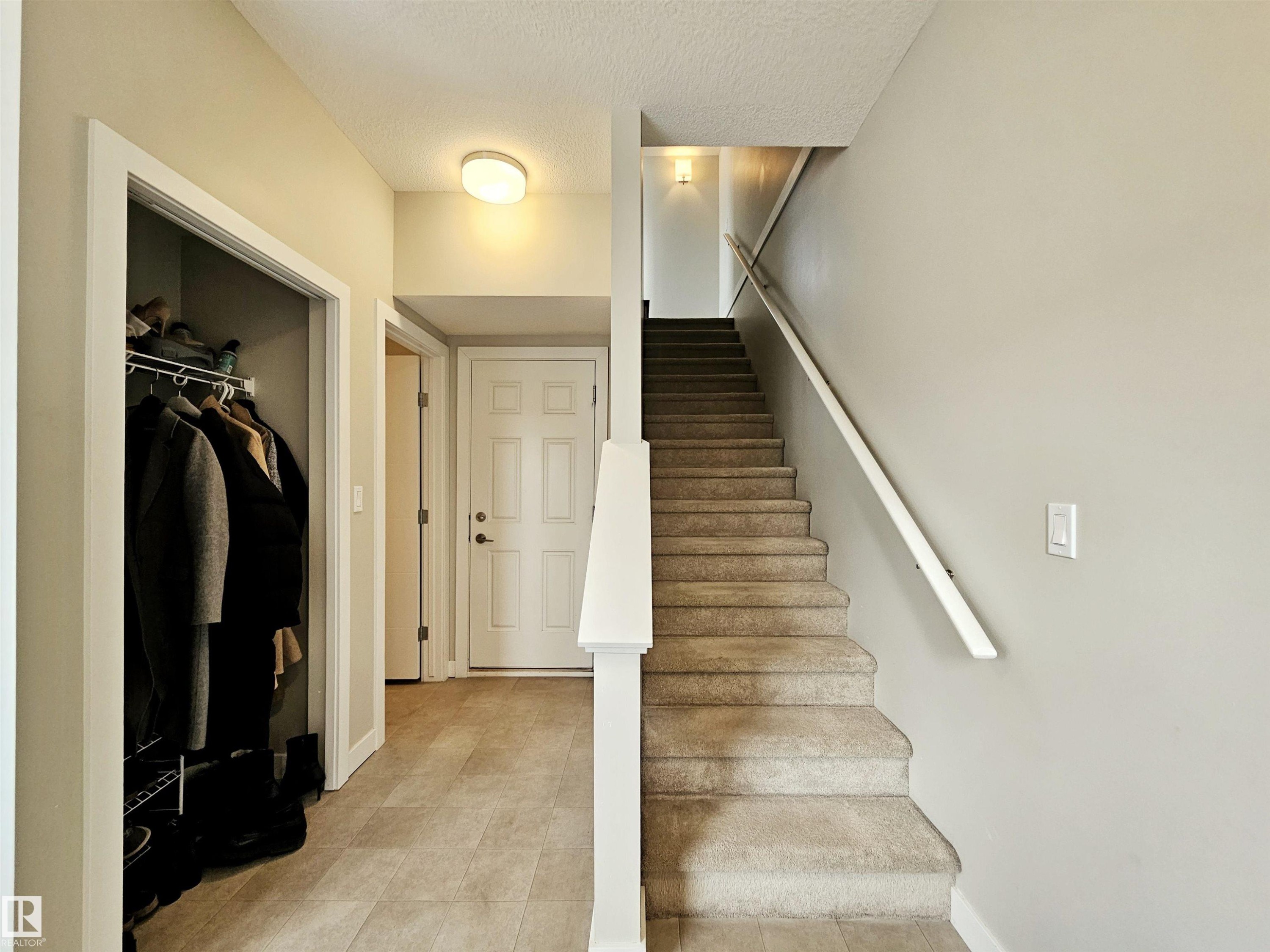 Staircase featuring baseboards and a textured ceiling - 129 2560 Pegasus Boulevard, Edmonton, AB - Indoor Photo Showing Other Room