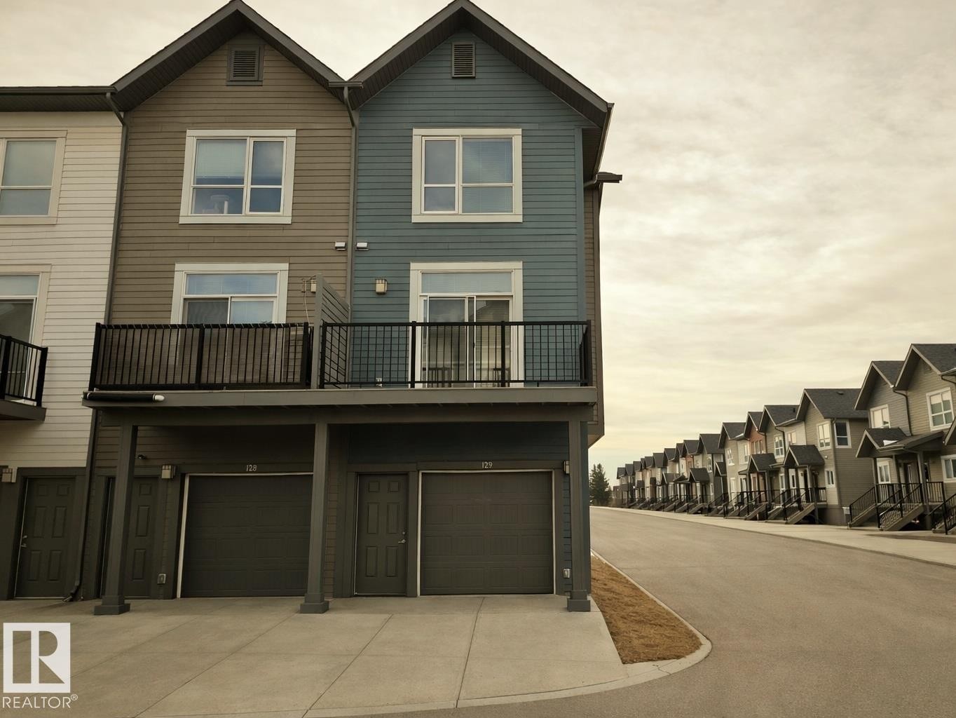 Back of house featuring a garage, a balcony, driveway, and a residential view - 129 2560 Pegasus Boulevard, Edmonton, AB - Outdoor With Balcony With Facade