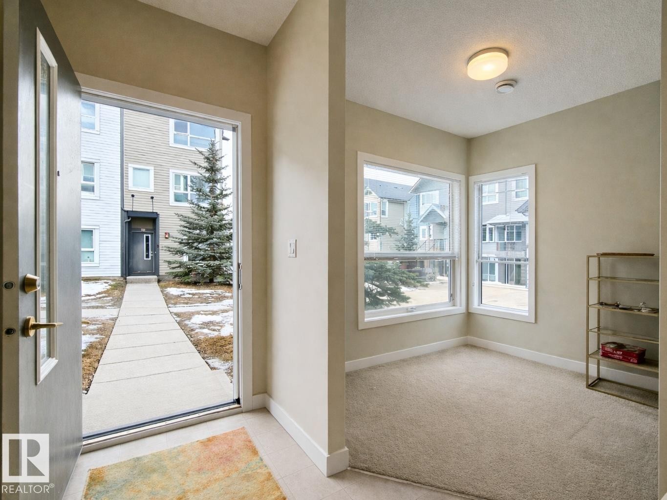 Entrance foyer with light tile patterned flooring and light colored carpet - 129 2560 Pegasus Boulevard, Edmonton, AB - Indoor Photo Showing Other Room