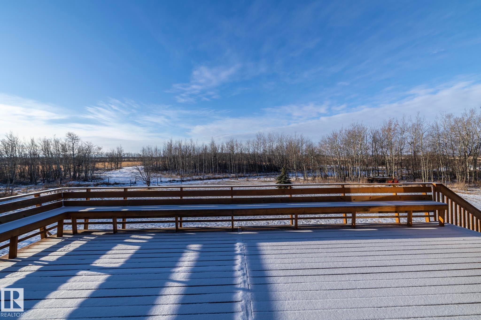 Wow! West facing deck, equipped with benches. Stairs give access to a concrete patio. Enjoy the sun while it's out and savour the sunsets. - 57524 Range Road 270, Rural Westlock County, AB - Outdoor With View