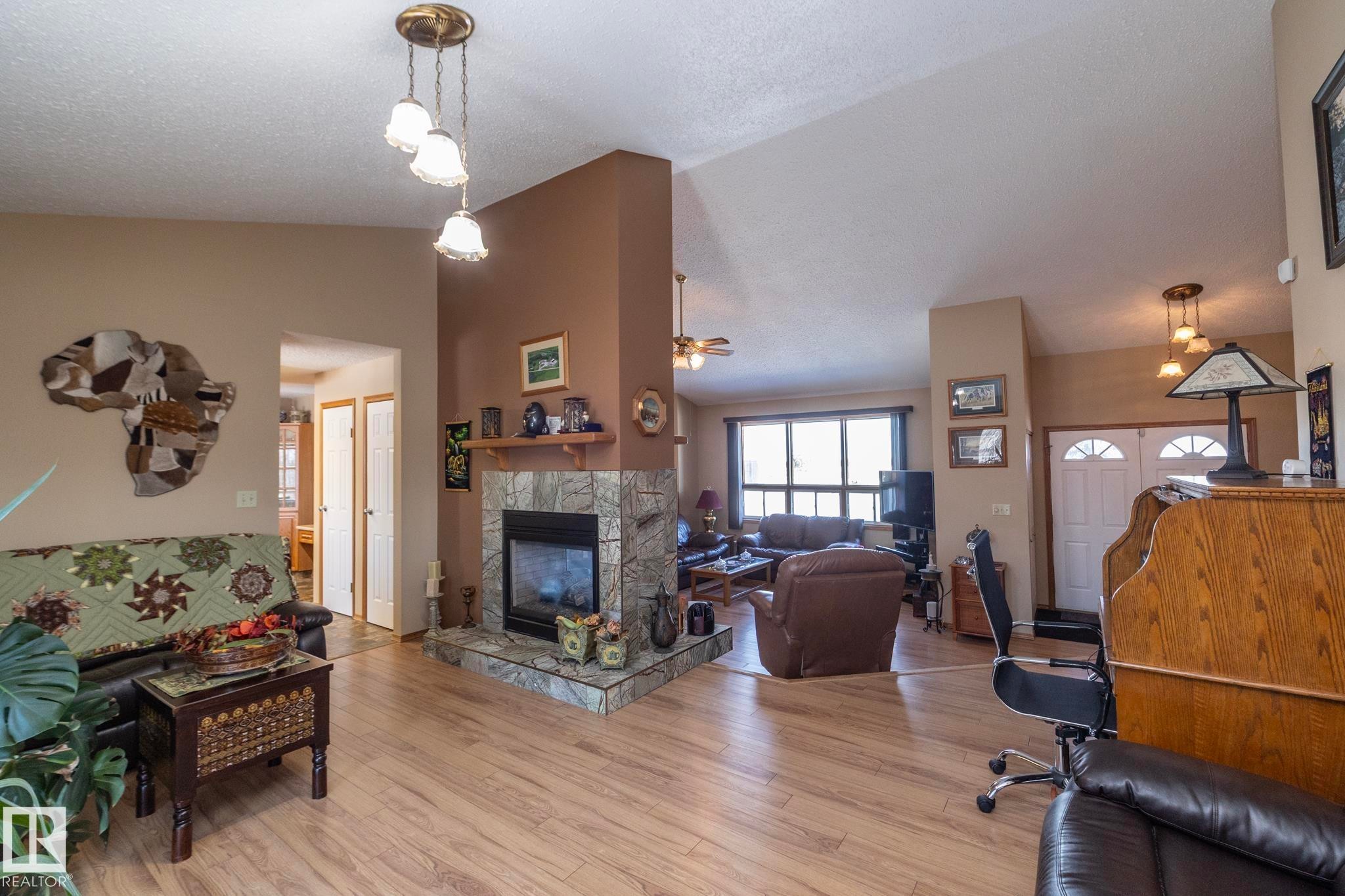 Looking from garden doors toward the living room and the main entryway. Everything flows and connects smoothly throughout the home - 57524 Range Road 270, Rural Westlock County, AB - Indoor Photo Showing Living Room With Fireplace