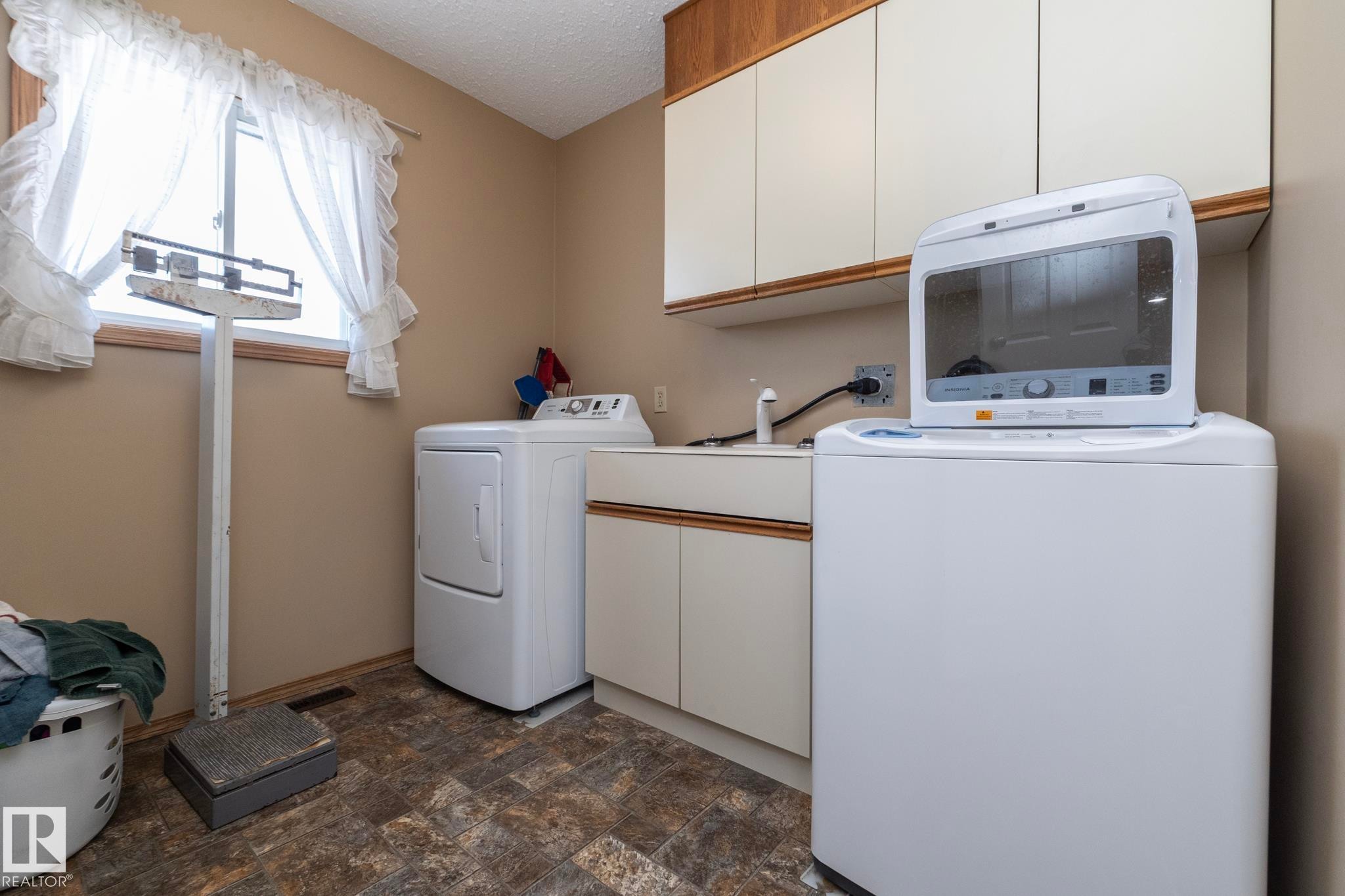 Near the stairway, garage and kitchen, the laundry room also has plenty of storage (if you need more!). Easily accessible from the garage & outside, "grubbies" can be removed without walking through the house--great idea! Also right by the powder room. - 57524 Range Road 270, Rural Westlock County, AB - Indoor Photo Showing Laundry Room