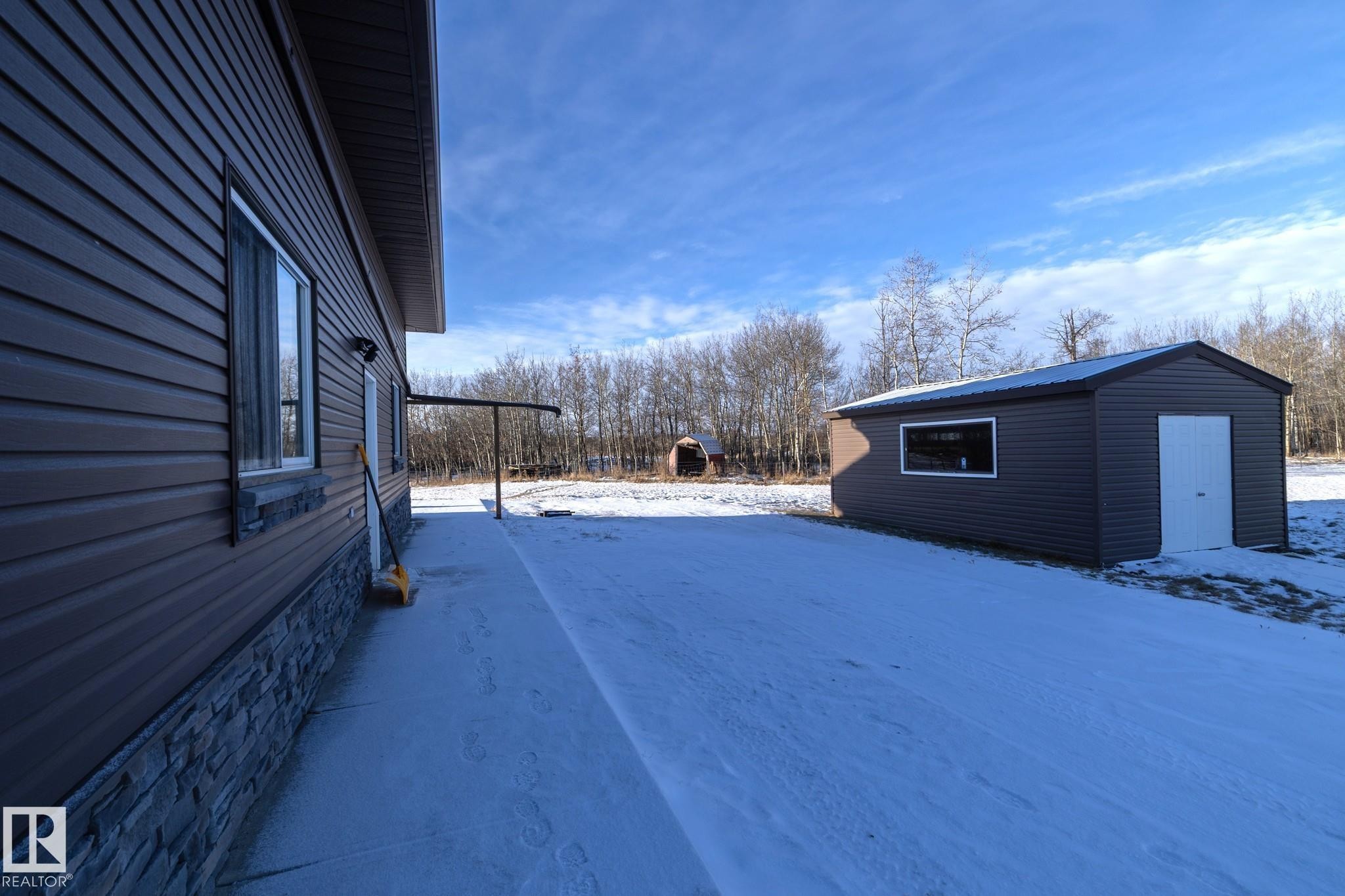 Side entrance to garage from additional parking area. Also a storage shed. There is a concrete walkway from here to the back of the house where the large patio area is located, with steps up to the deck. - 57524 Range Road 270, Rural Westlock County, AB - Outdoor With Exterior