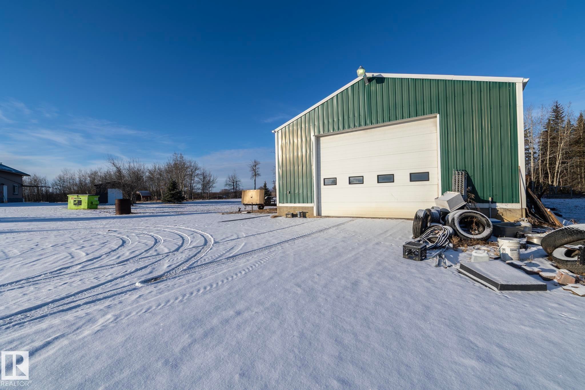This shop is a short walk from house. Metal clad, heated, insulated, furnace/boiler, in-floor heating, concrete floor, +wood burning stove. Workbenches along windows, tall o/head door. Ceiling has access panel & a fan or two. Many possibilities. - 57524 Range Road 270, Rural Westlock County, AB - Outdoor With Exterior