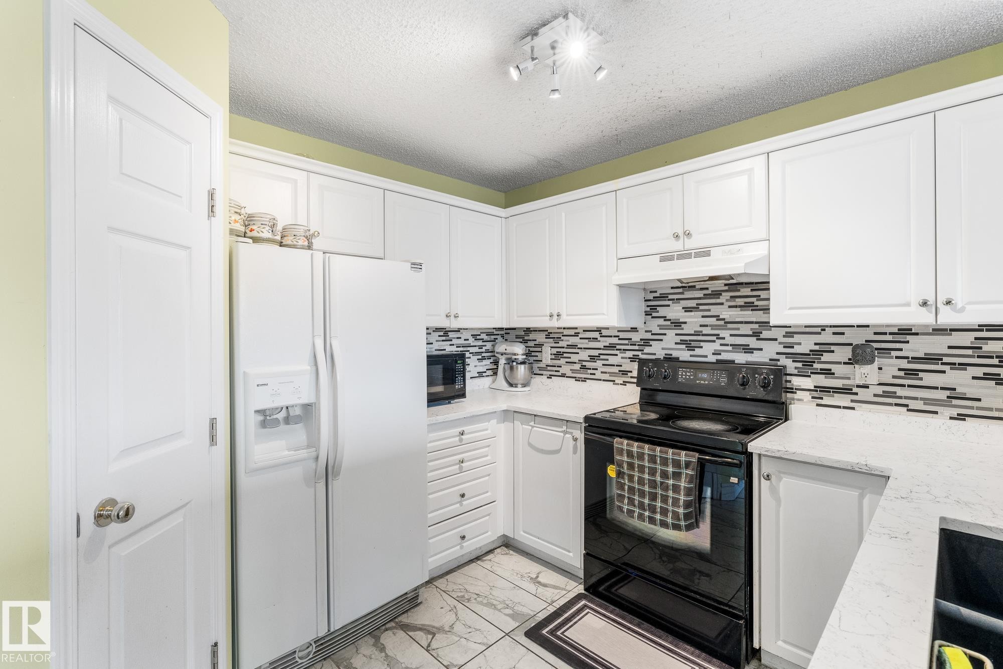 Kitchen featuring black appliances, light marble finish floors, white cabinets, a textured ceiling, and backsplash - 13148 151 Avenue, Edmonton, AB - Indoor Photo Showing Kitchen
