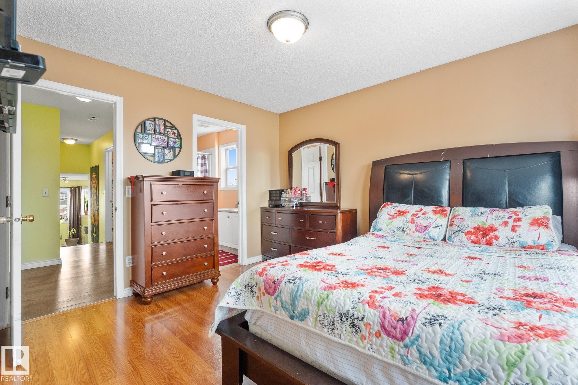Bedroom featuring light wood-style floors, multiple windows, and a textured ceiling - 13148 151 Avenue, Edmonton, AB - Indoor Photo Showing Bedroom