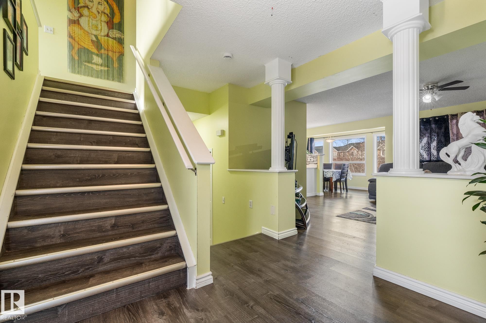 Stairs featuring decorative columns, a textured ceiling, wood finished floors, and a ceiling fan - 13148 151 Avenue, Edmonton, AB - Indoor Photo Showing Other Room