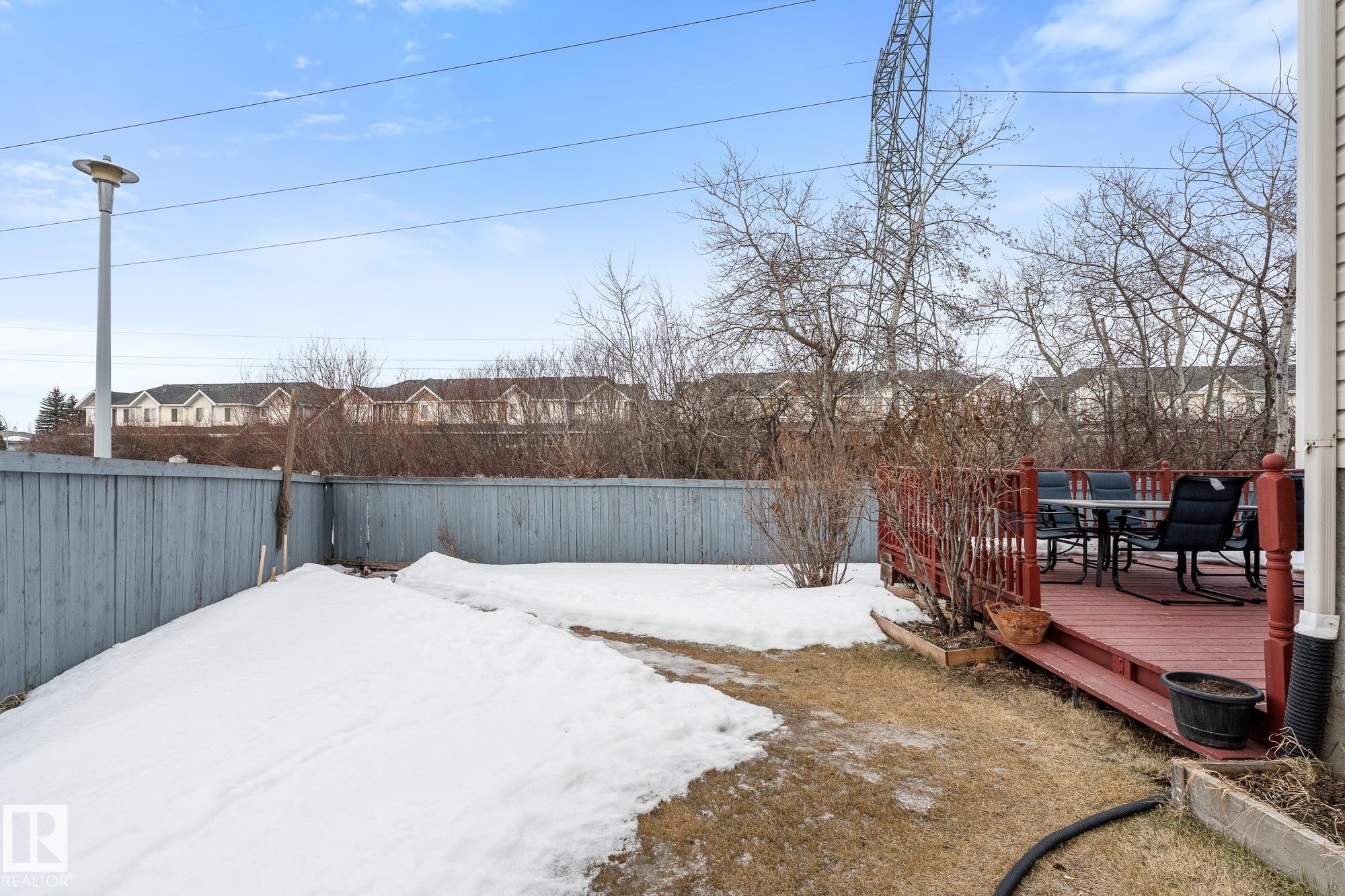 Yard layered in snow with a wooden deck, a fenced backyard, outdoor dining space, and a residential view - 13148 151 Avenue, Edmonton, AB - Outdoor