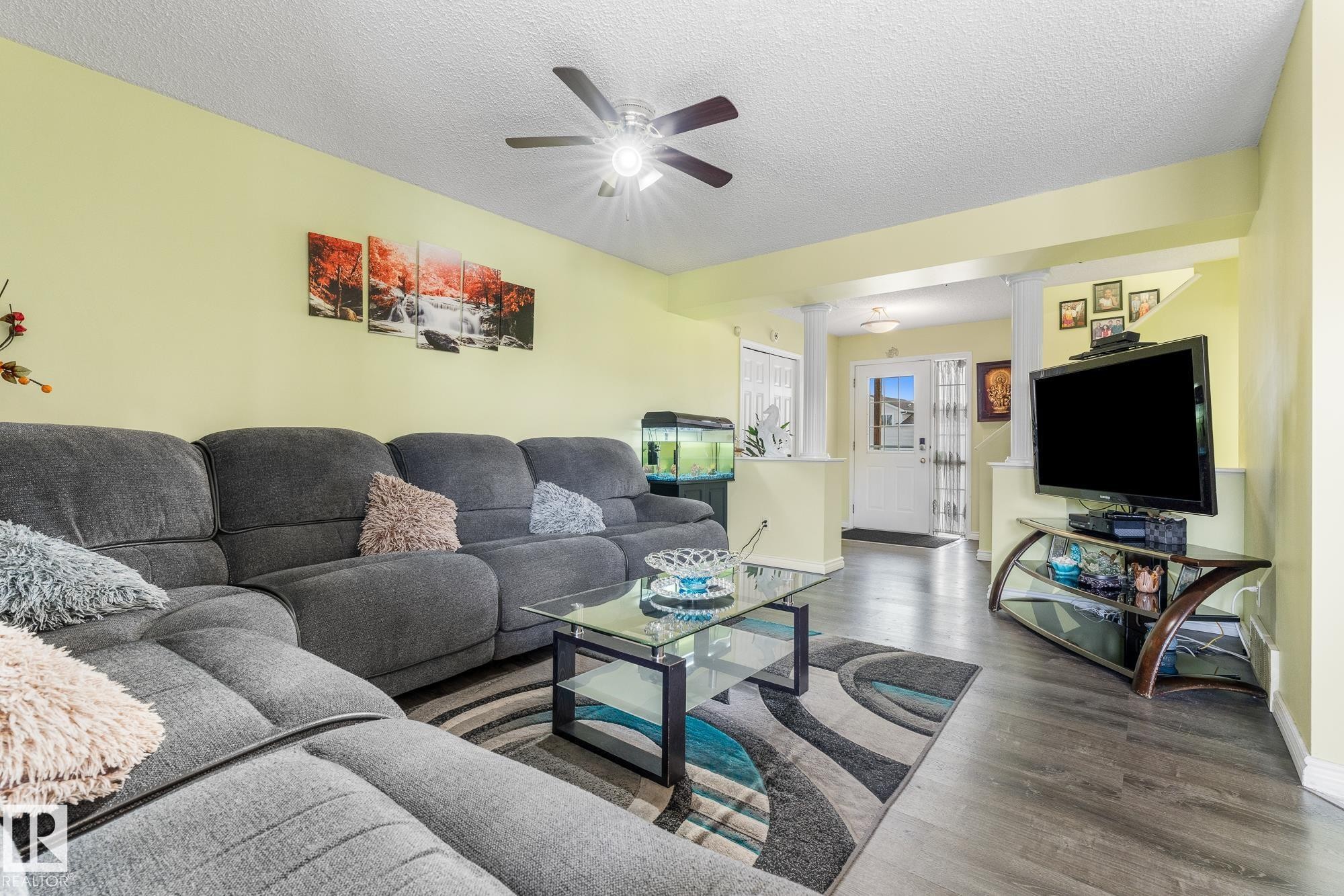 Living room with ornate columns, dark wood-style flooring, a ceiling fan, and a textured ceiling - 13148 151 Avenue, Edmonton, AB - Indoor Photo Showing Living Room